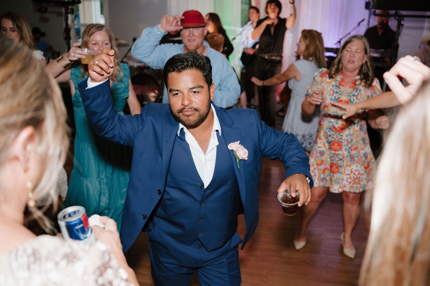 Wedding reception dance floor filled with guests celebrating in a beautifully lit venue.