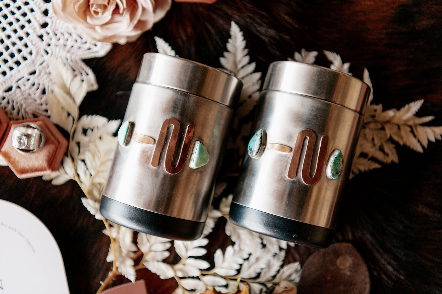 Two metallic cylindrical containers decorated with floral elements.