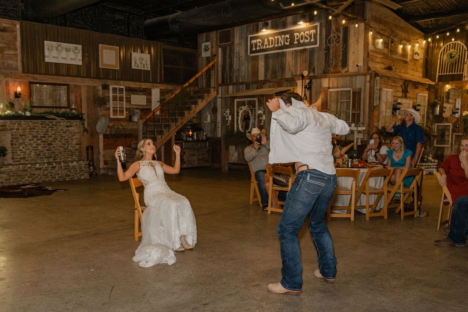 A couple dances joyfully in a rustic barn wedding reception.