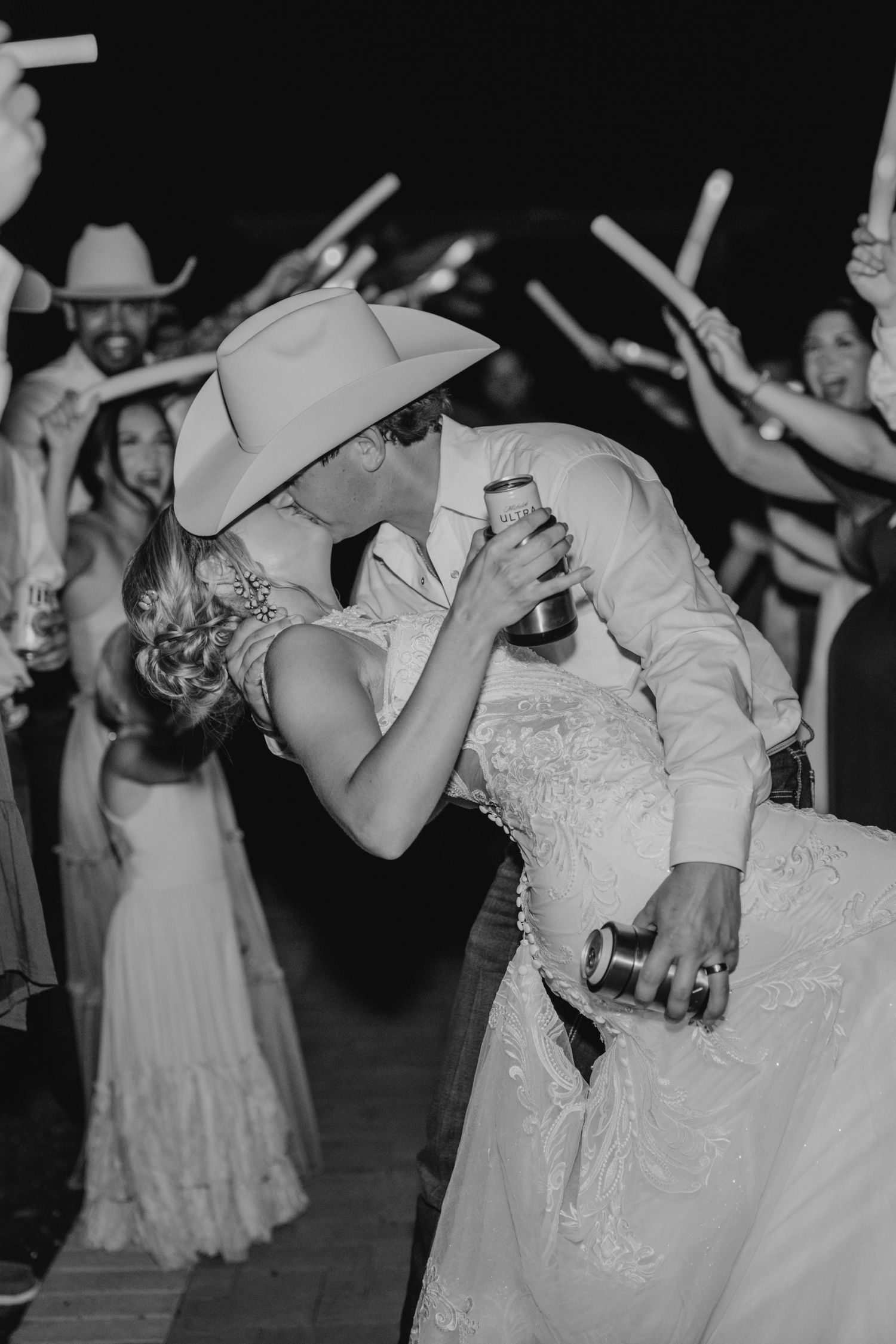 Black and white photo of newlyweds dancing at night surrounded by guests with sparklers.