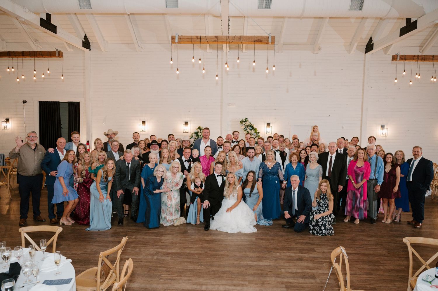A large group photo of the bride, groom, and their wedding guests gathered together.