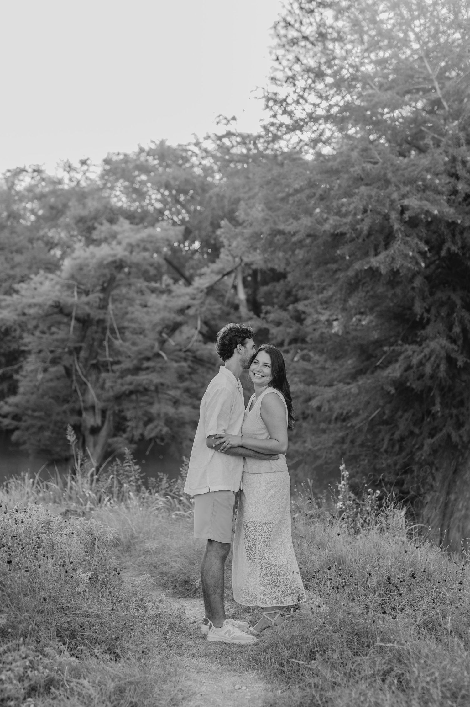 A series of black and white photos capturing intimate moments between a couple in nature.