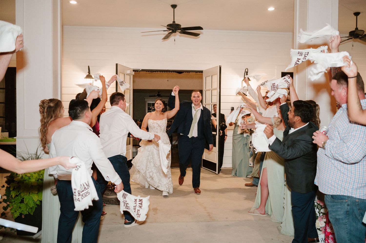 Wedding guests dancing and celebrating with arms raised during an energetic reception.