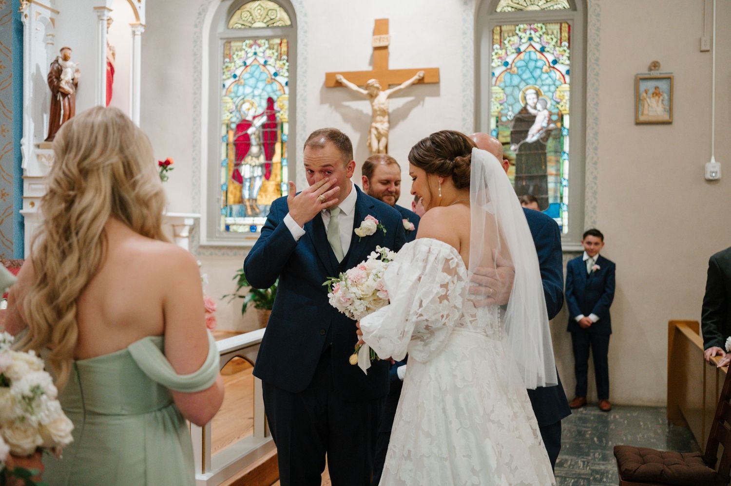 Wedding ceremony taking place in a traditional Catholic church with stained glass windows.