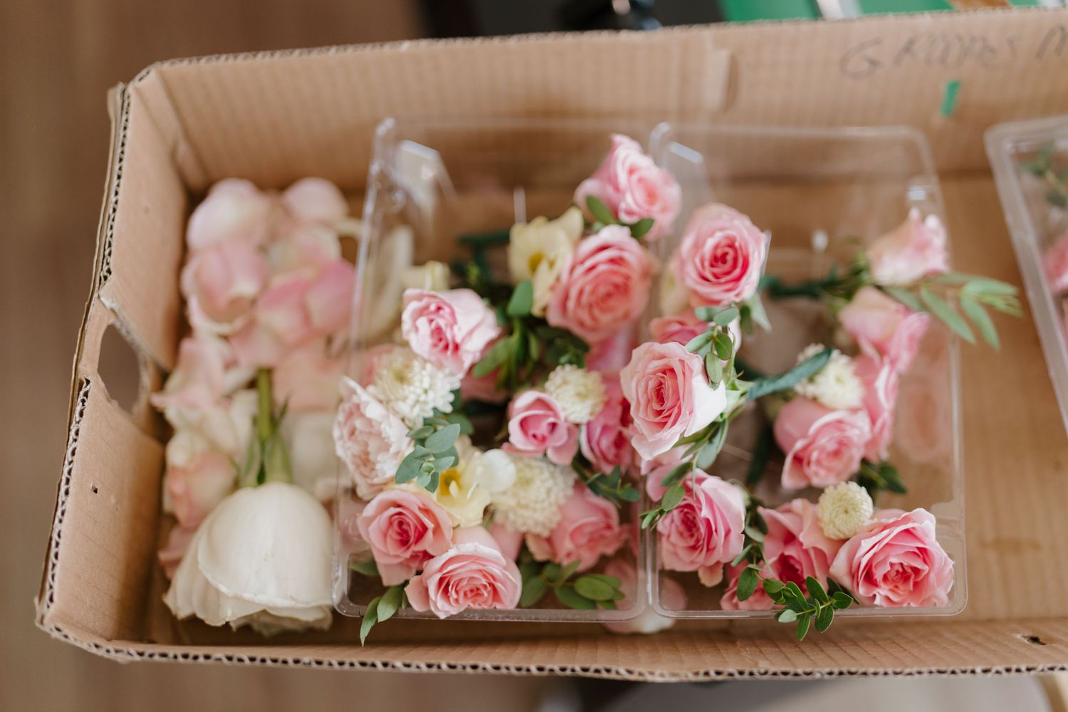 Pink roses with delicate petals arranged in wooden boxes for wedding decor.