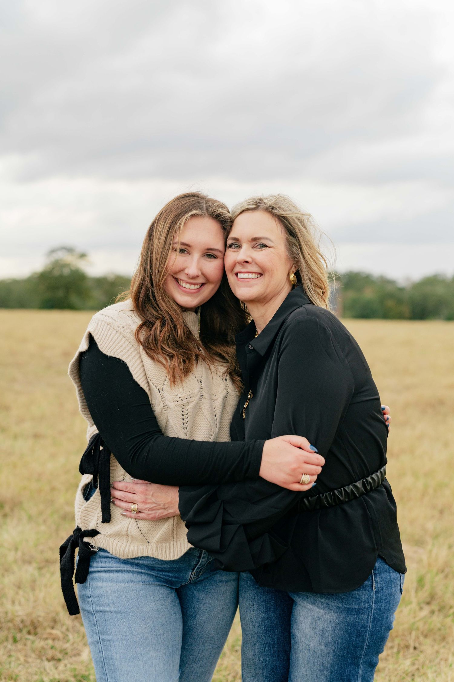 Two people sharing a warm embrace and genuine smiles in an autumn field.