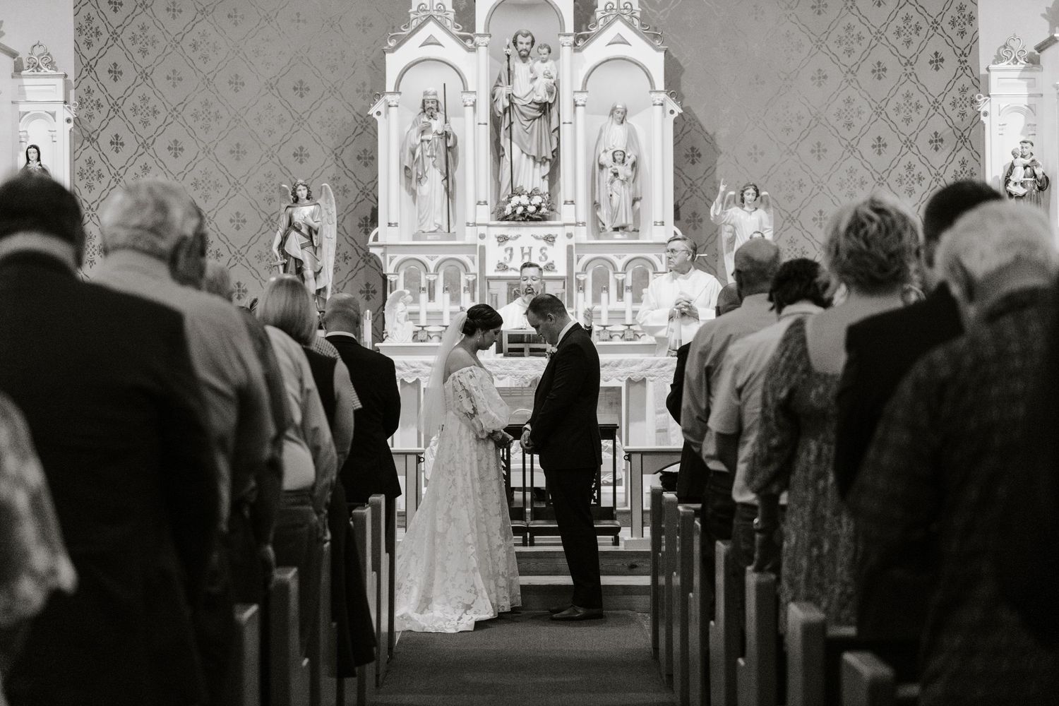Church interior with ornate altar and guests seated for wedding ceremony.