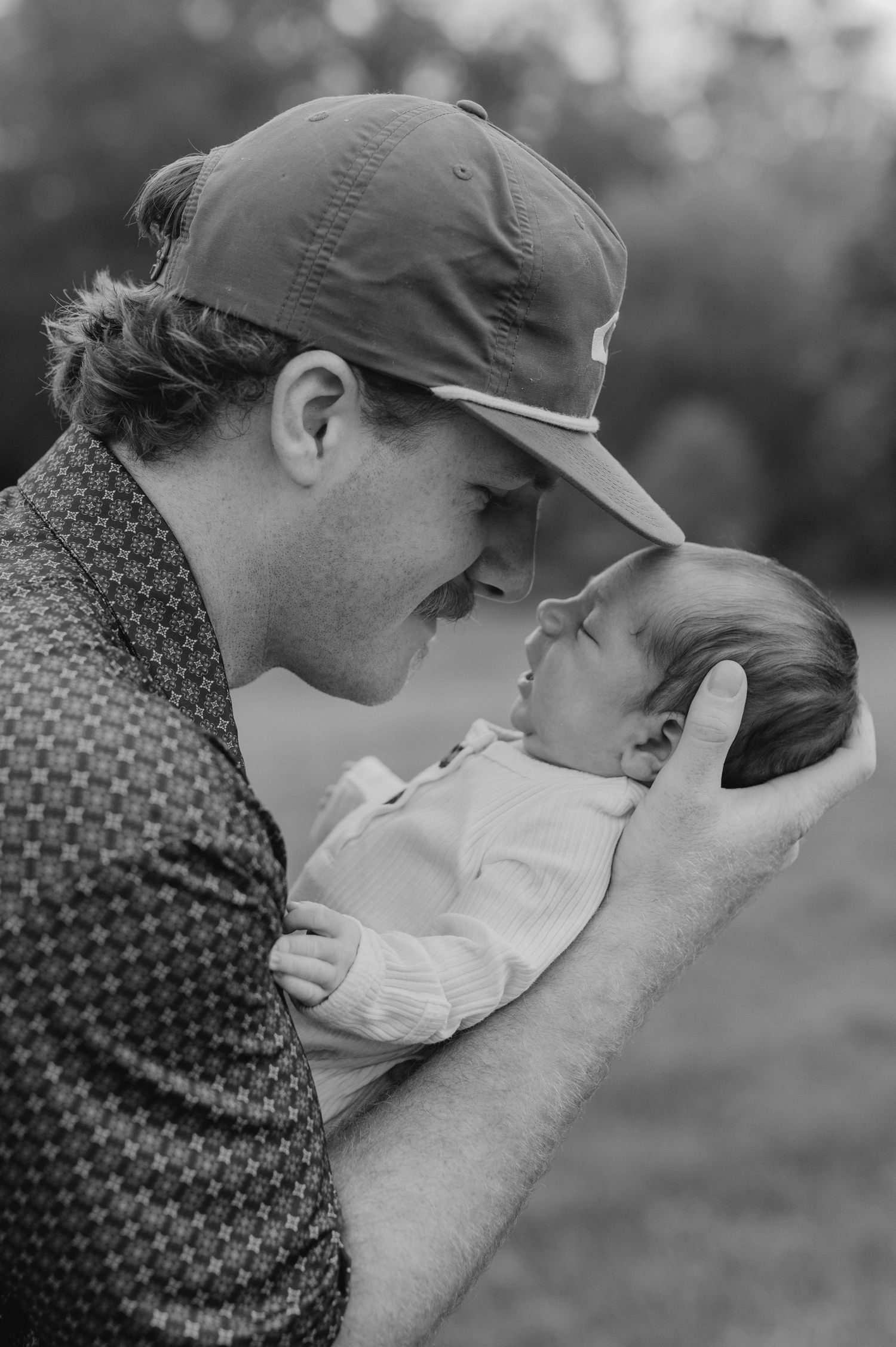 A romantic black and white photo series showcasing two people sharing tender kisses in a natural outdoor setting.