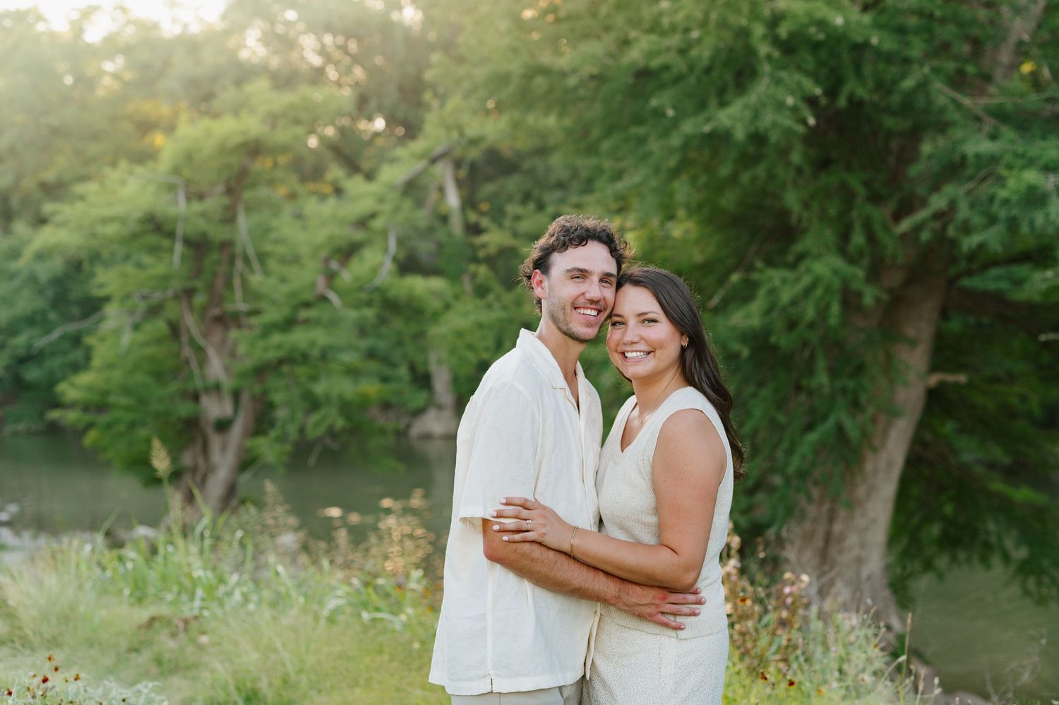 A couple embracing in a sunlit garden setting during their engagement session.