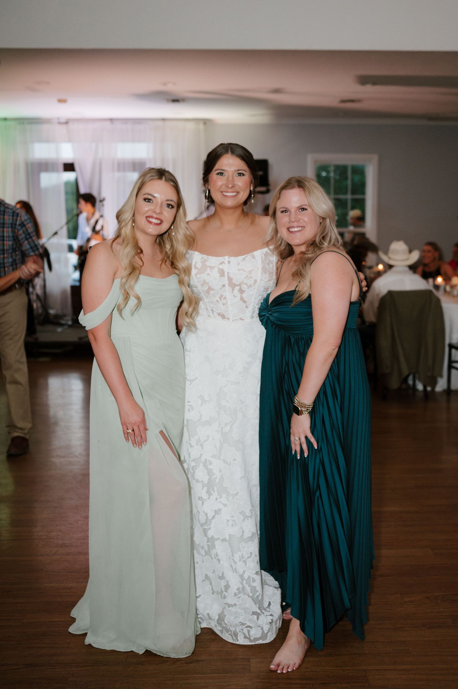 Wedding party members pose together wearing mint green and white dresses.