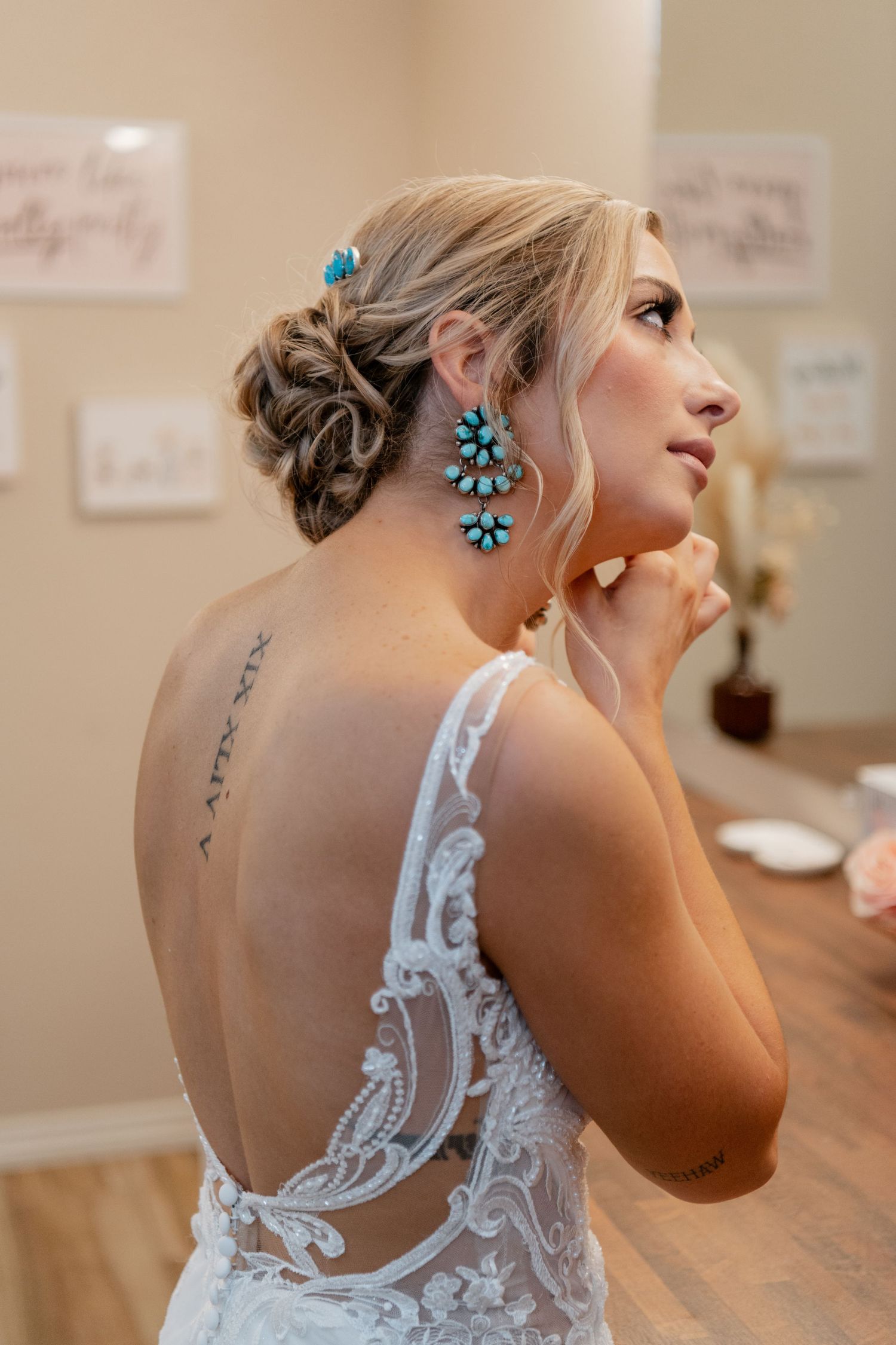 Elegant bridal attire featuring a lace back wedding dress and turquoise statement earrings.