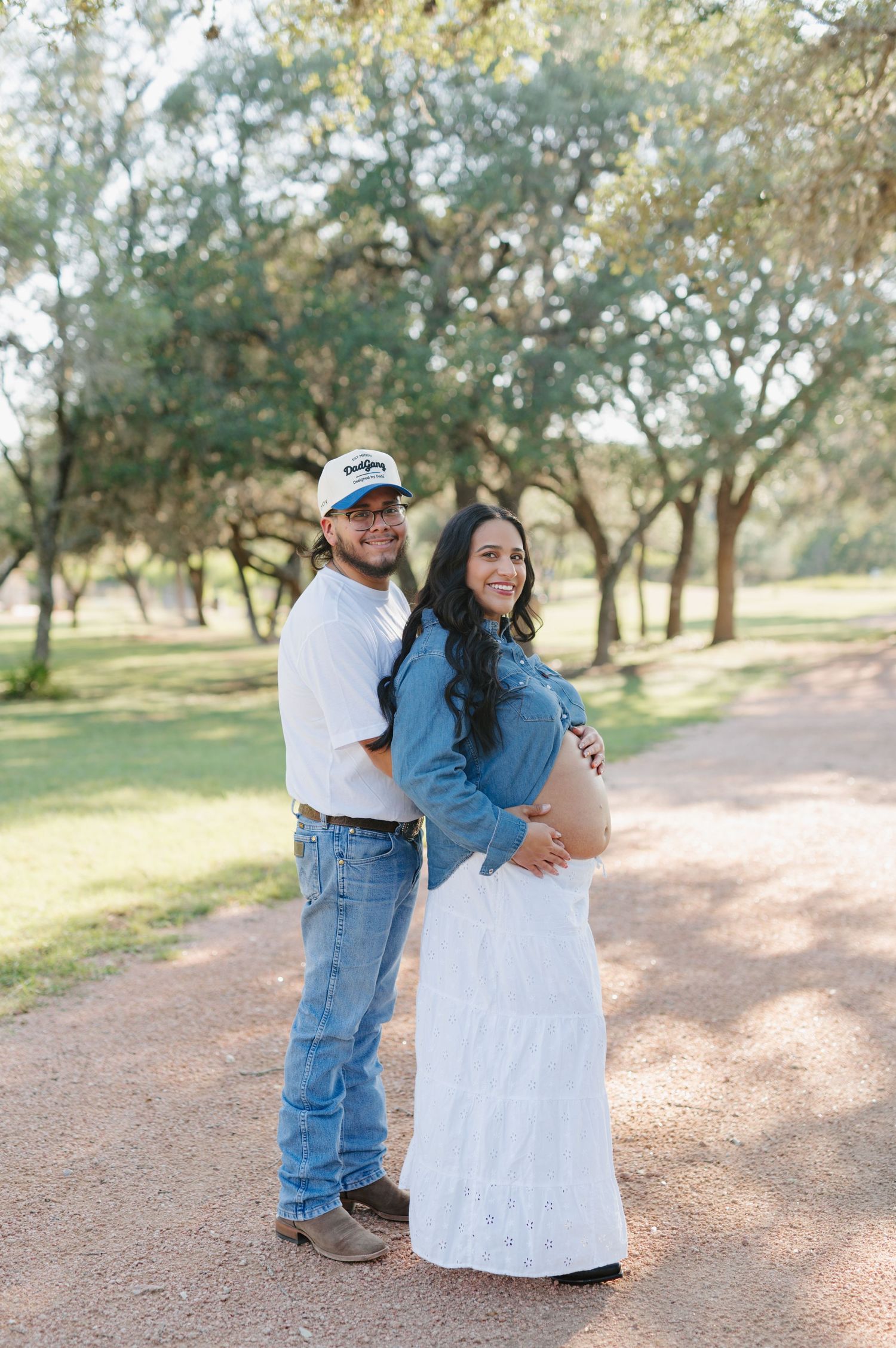 A couple shares an intimate moment during their maternity photo session in a serene outdoor setting.