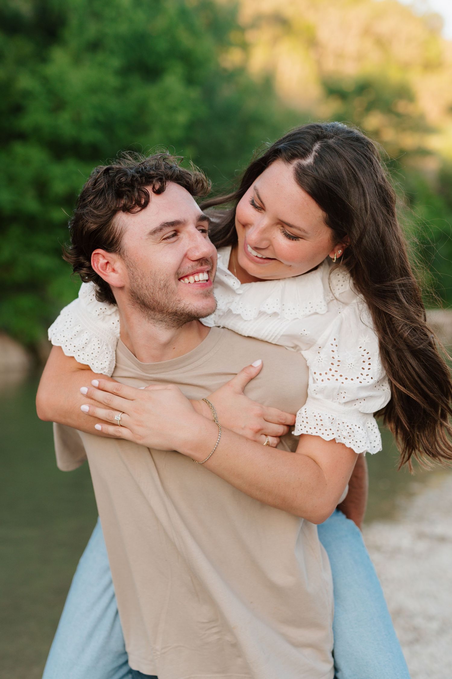 Playful couple laughing and embracing outdoors in natural lighting.