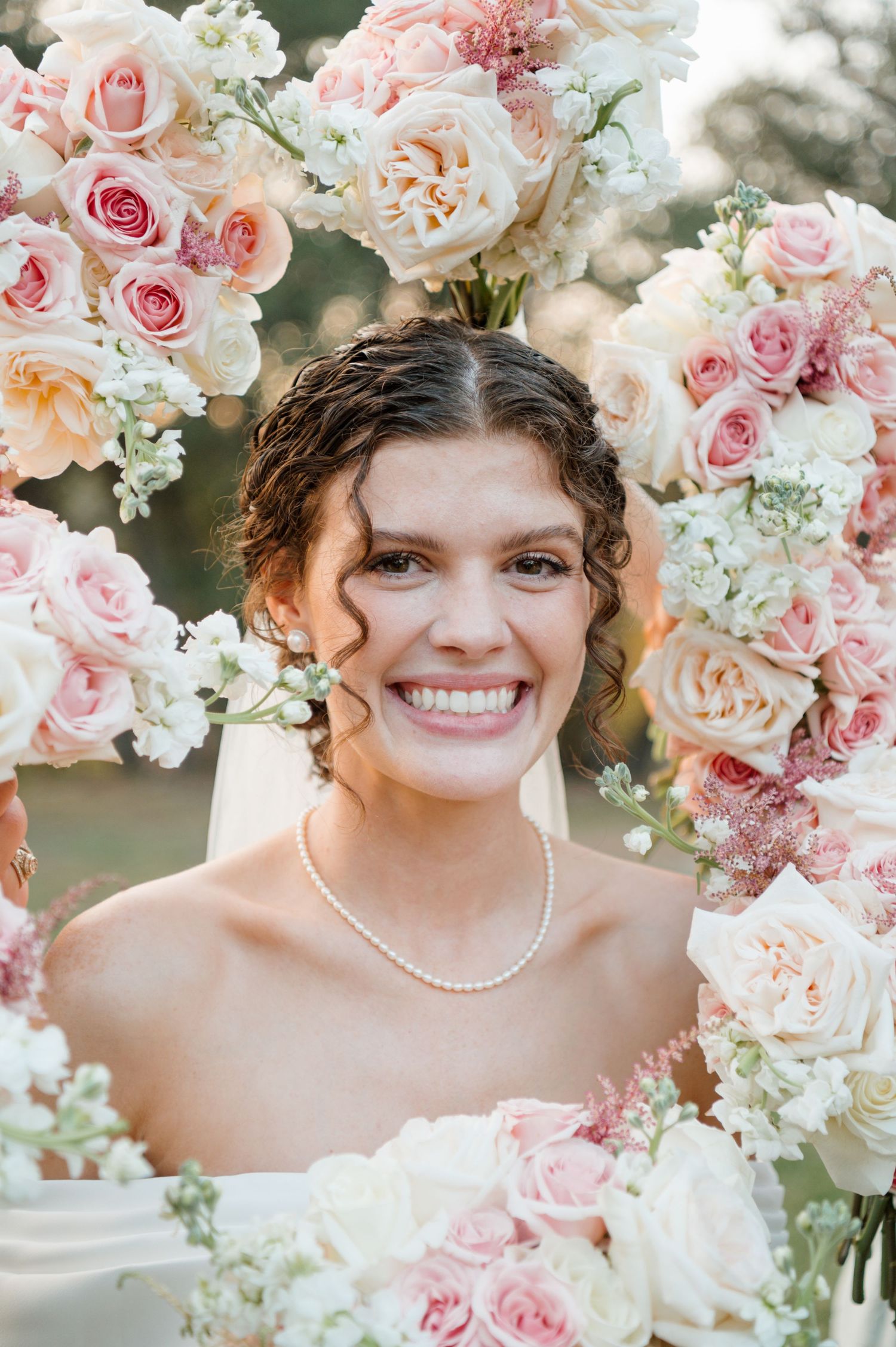 Wedding portrait framed by beautiful pink and white roses with soft natural lighting.