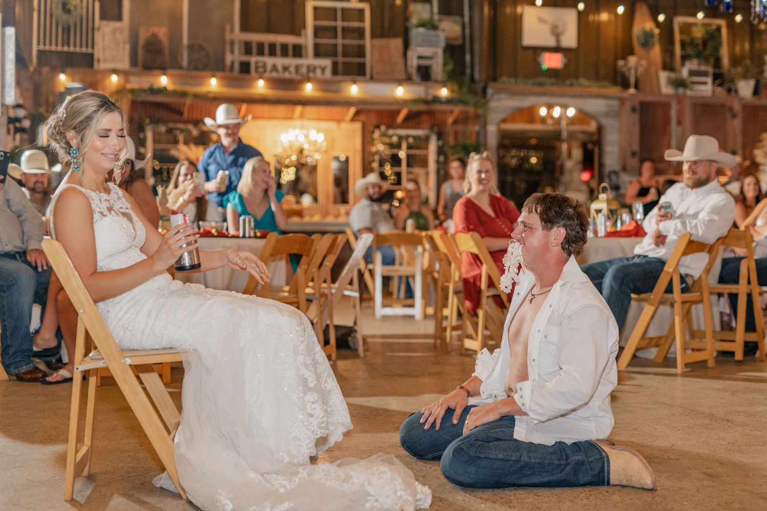 A traditional wedding garter ceremony takes place in a rustic barn reception venue.