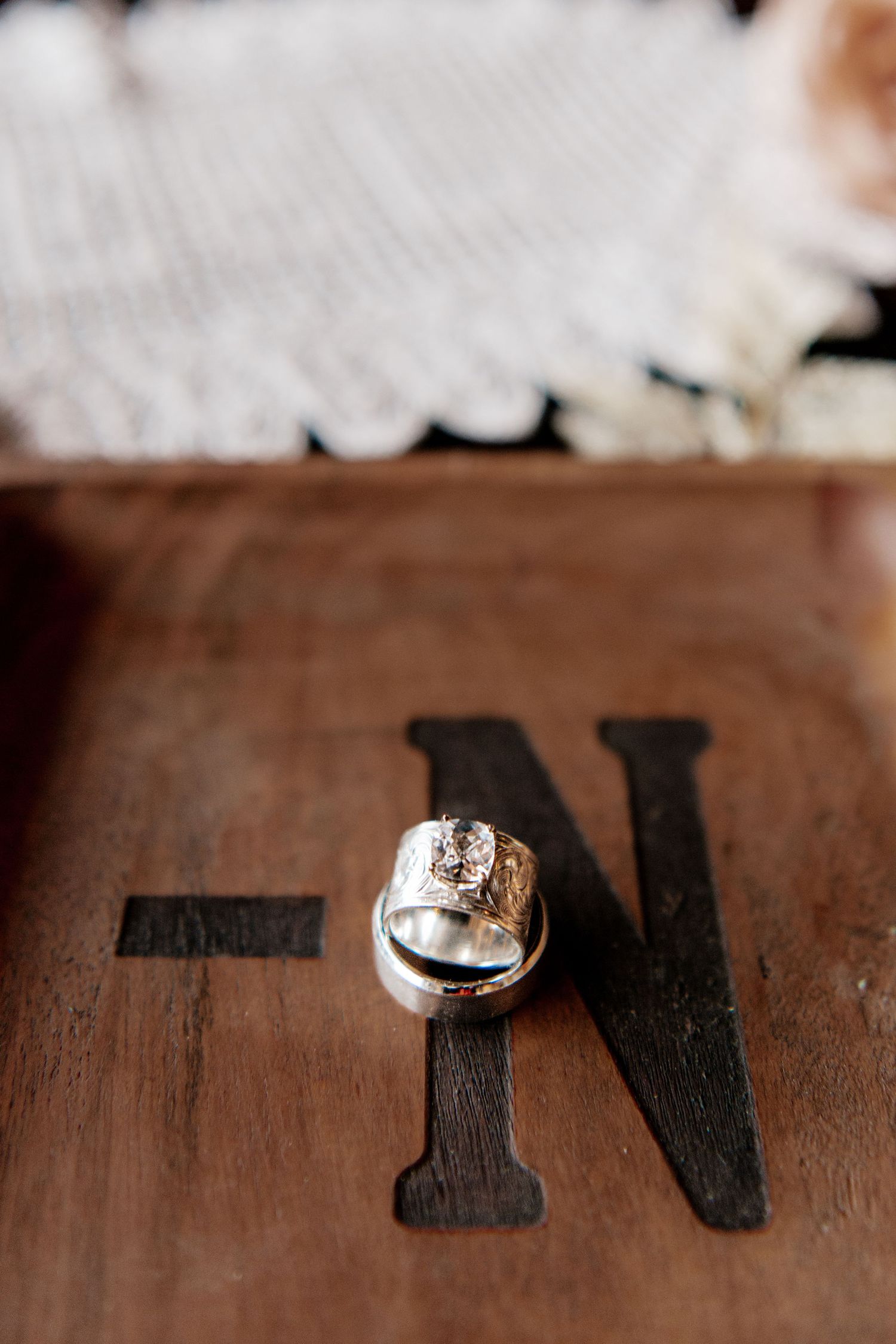 Wedding rings displayed on a wooden surface with black letter N painted on it.
