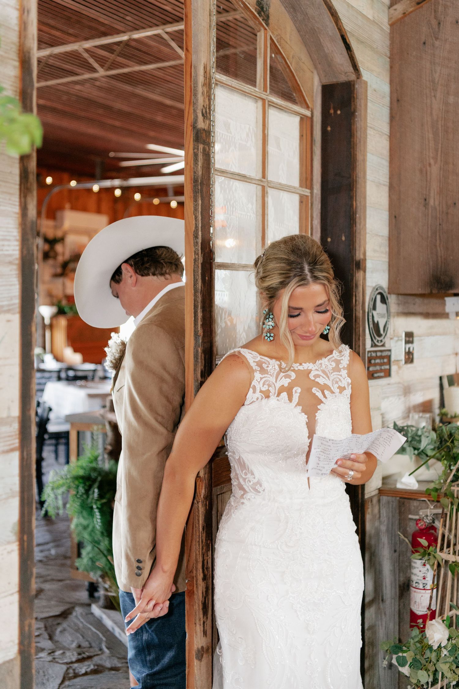 A tender first look moment captured between couple in rustic venue setting with string lights.