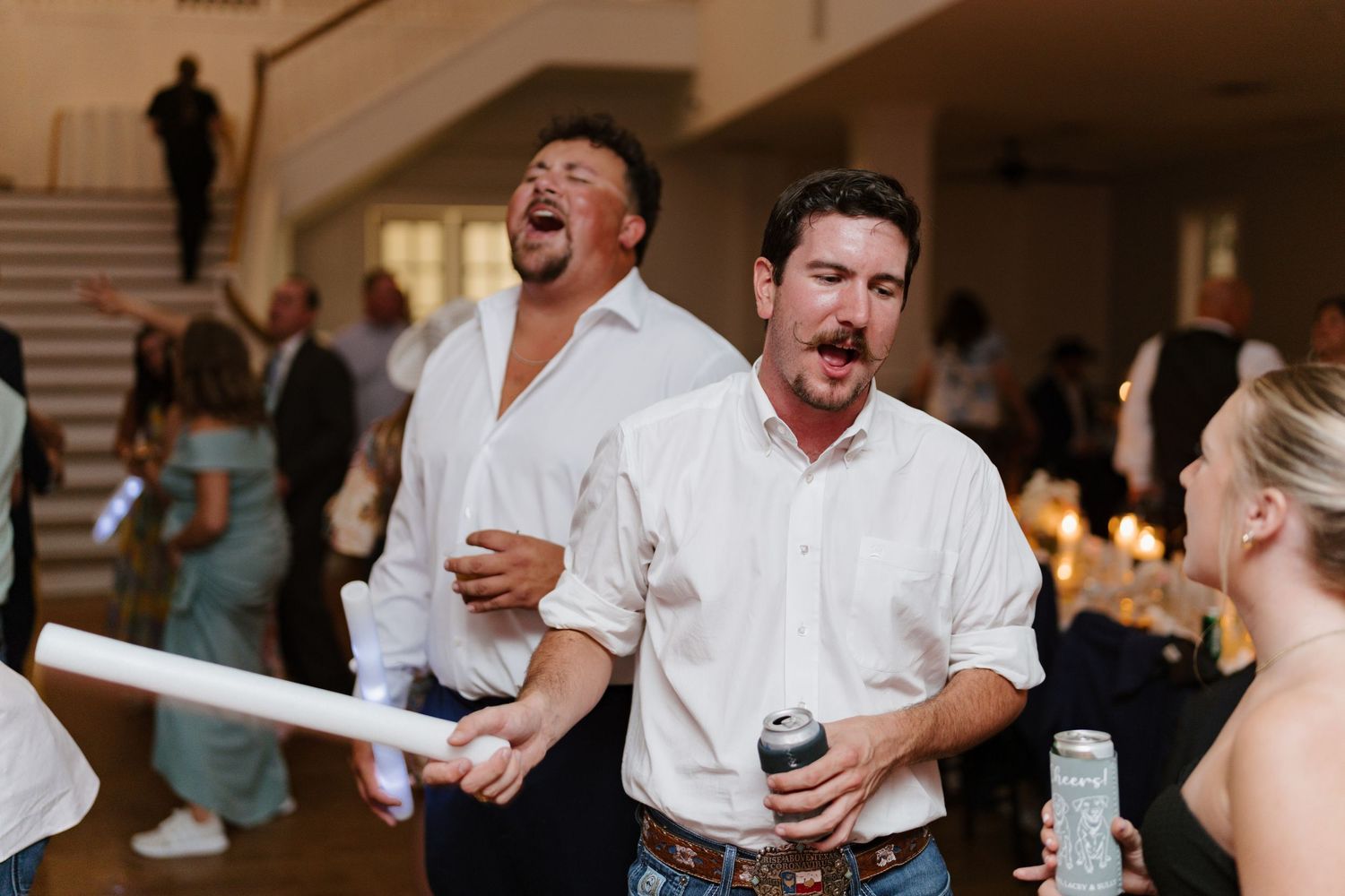 Wedding guests dancing and celebrating enthusiastically at indoor reception venue.