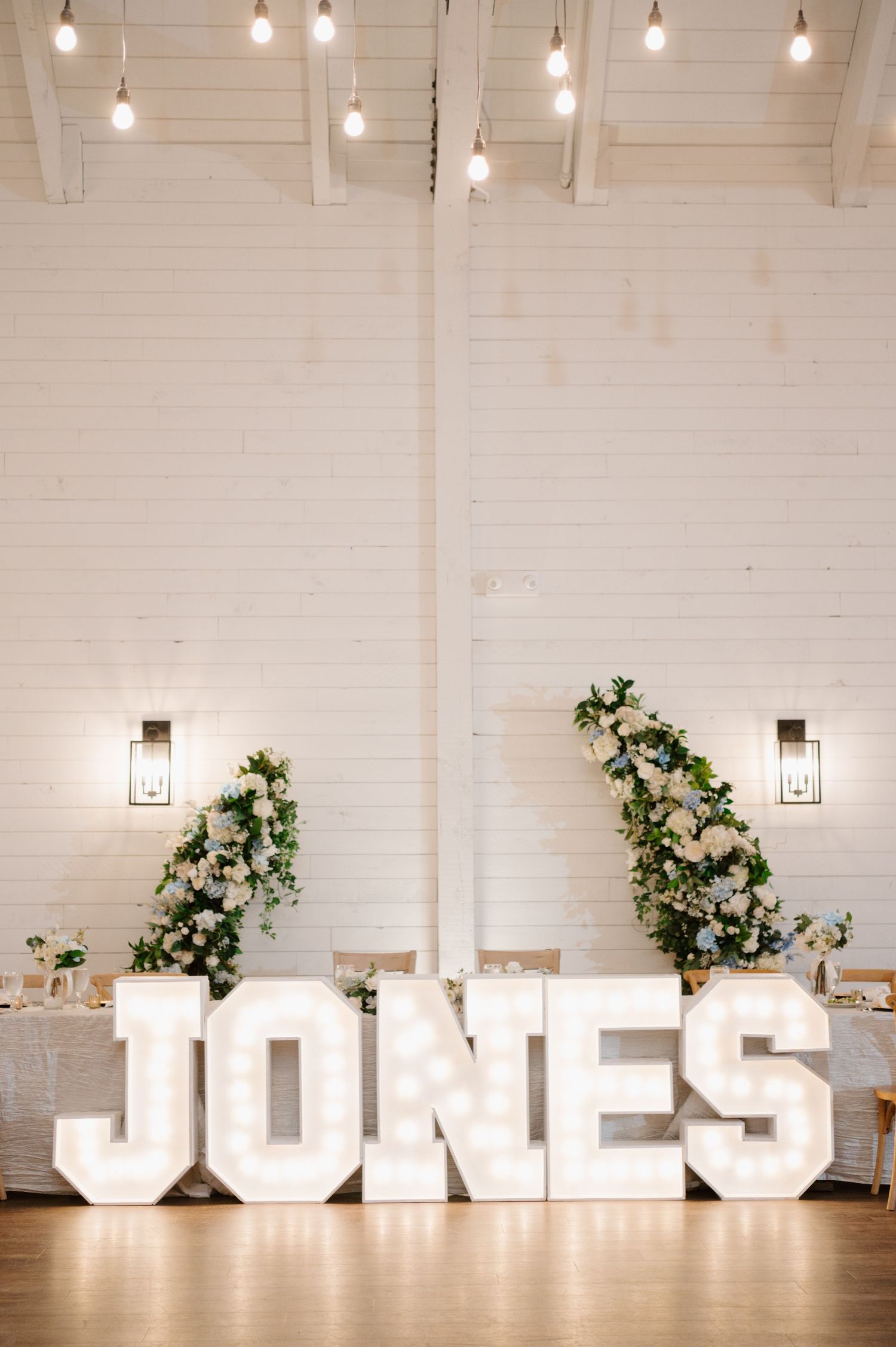 A wedding reception with large floral arrangements and the word 'JONES' displayed in large letters.