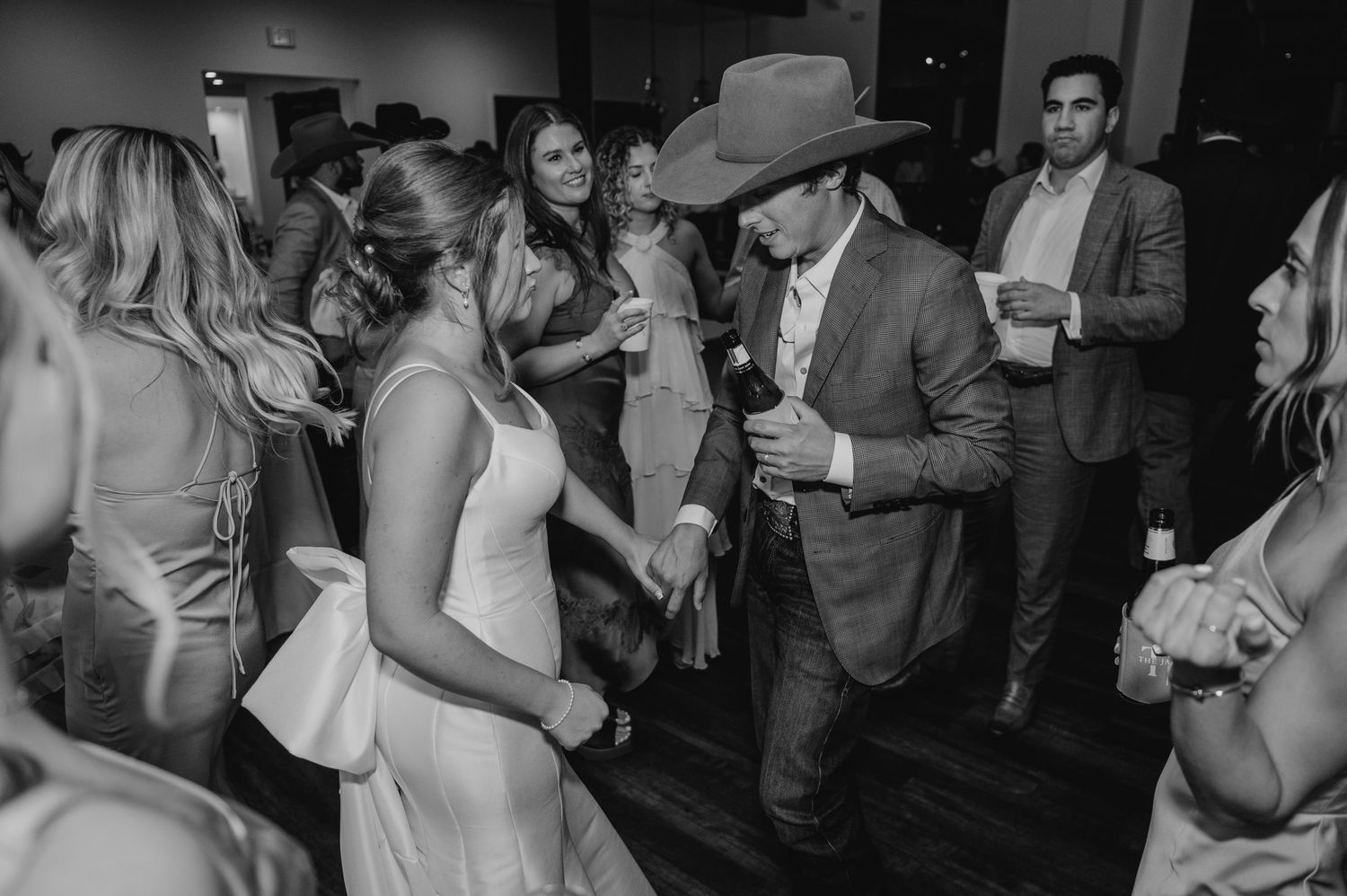 People dancing and celebrating at a lively wedding reception party on a crowded dance floor.