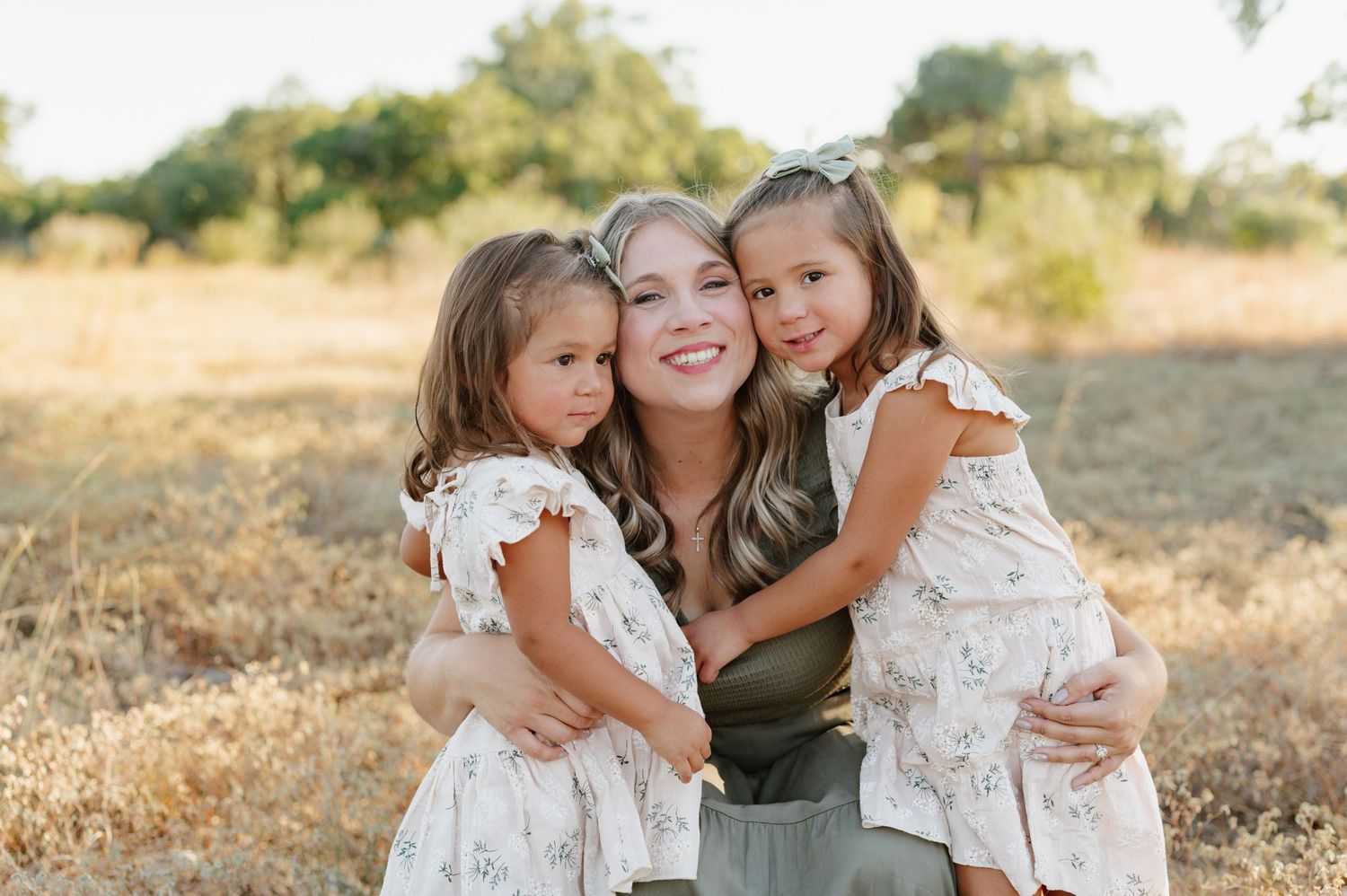 A loving family moment captured in a golden field during sunset, showing tender embraces and joyful expressions.