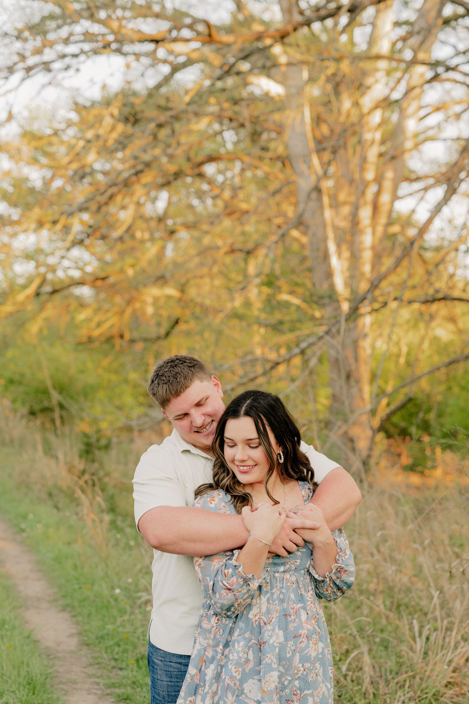 A couple shares an intimate moment on a nature trail during golden hour.