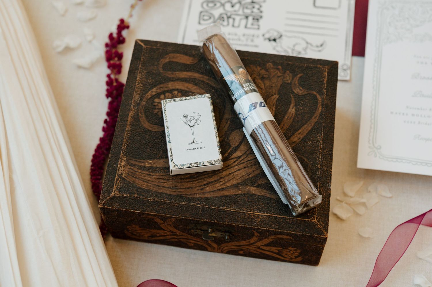 Rustic wooden box with calligraphy supplies and handwritten notes arranged on a white surface.