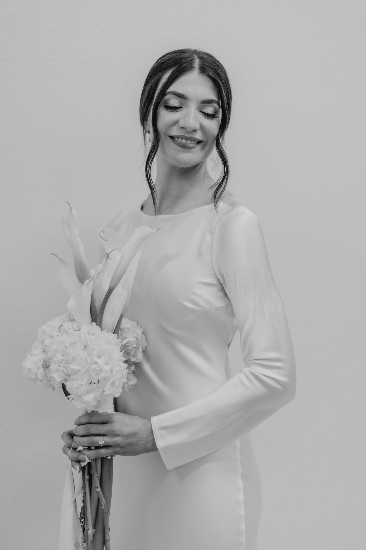 Elegant bridal portraits in white showing close-up details of a simple long-sleeved wedding dress and bouquet.