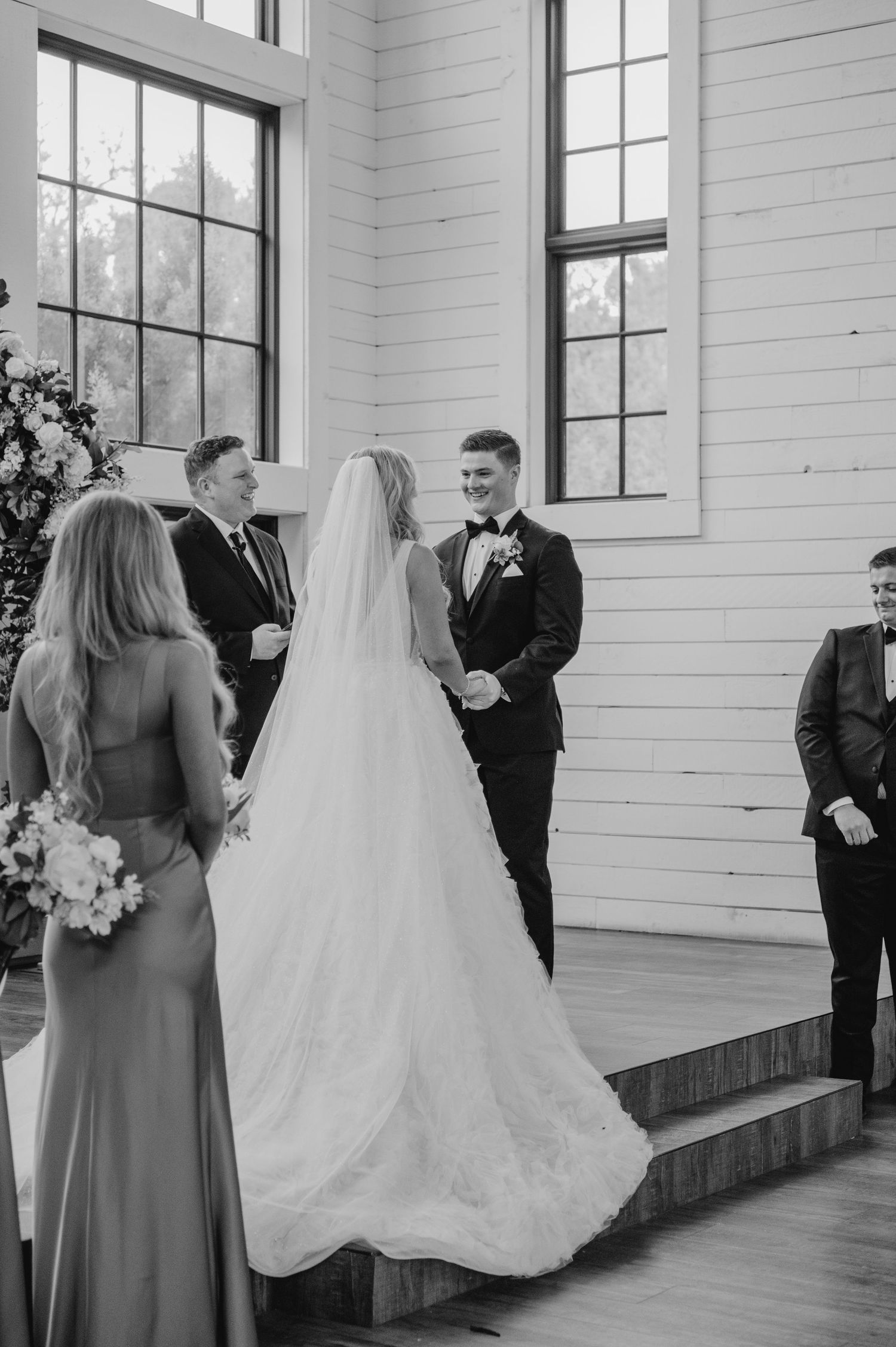 A bride and groom standing on the steps of a building, surrounded by their wedding party.