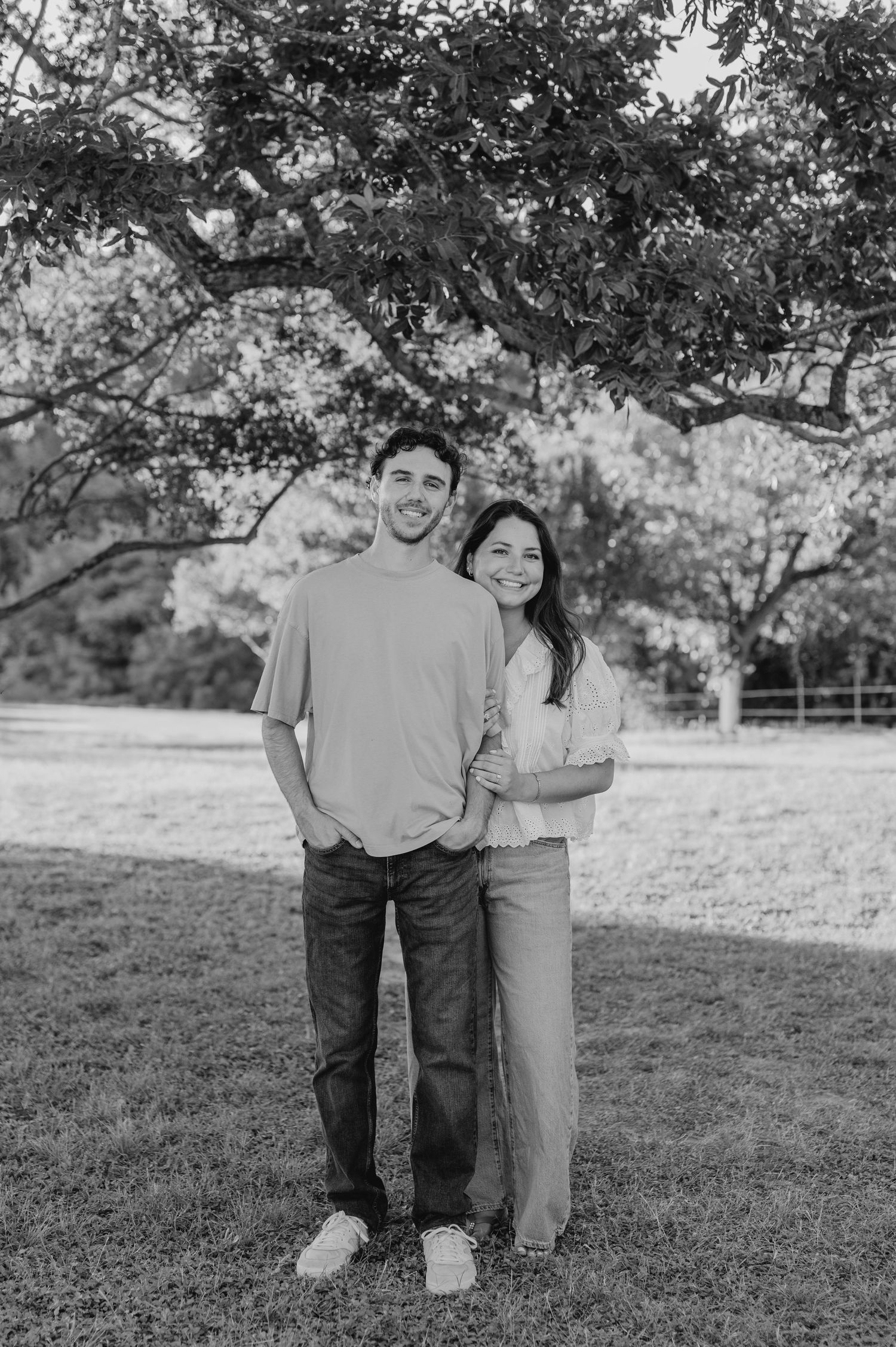 Black and white portraits of a couple standing together on a grassy hillside.