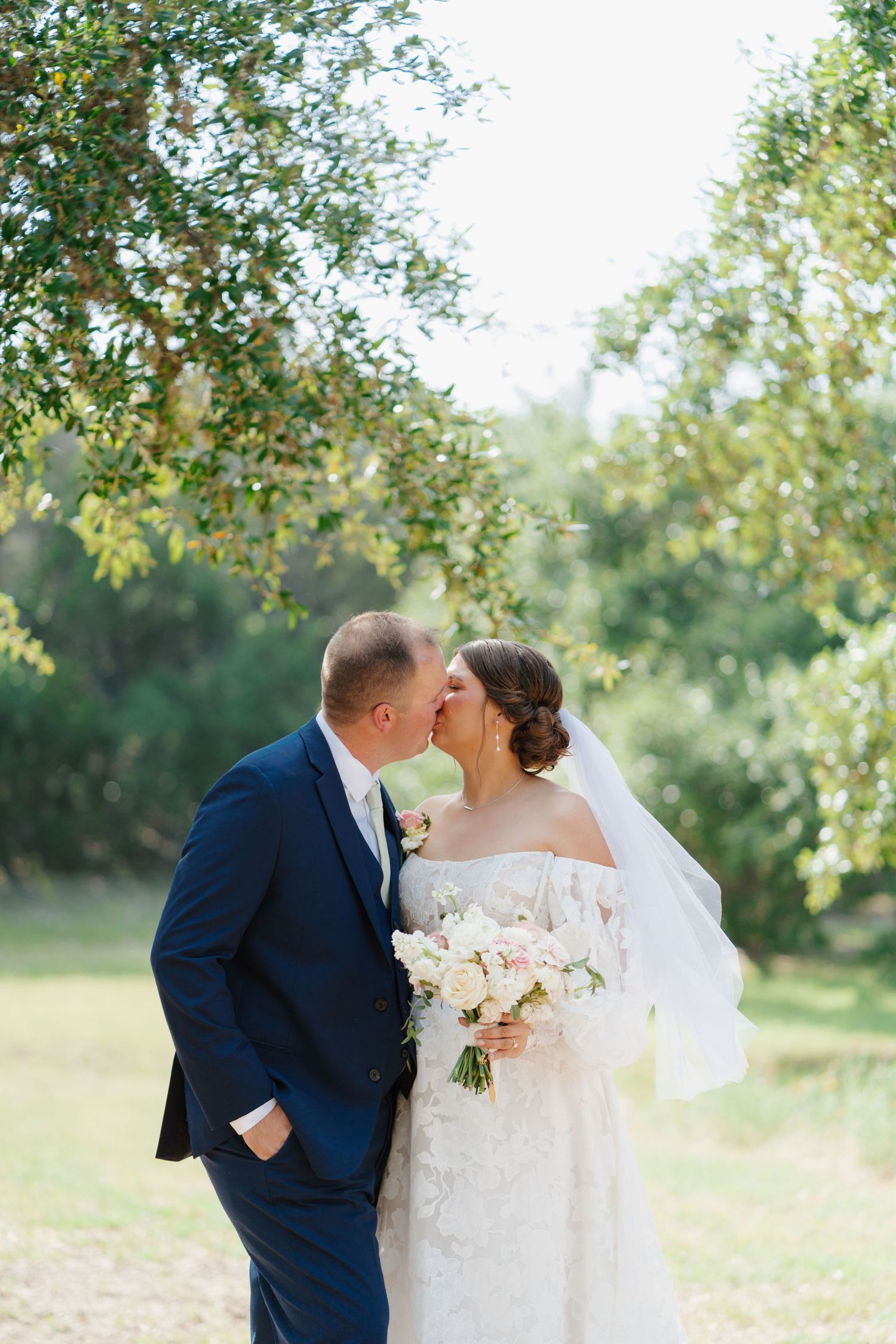 Romantic wedding portraits captured in a sunlit orchard garden setting.