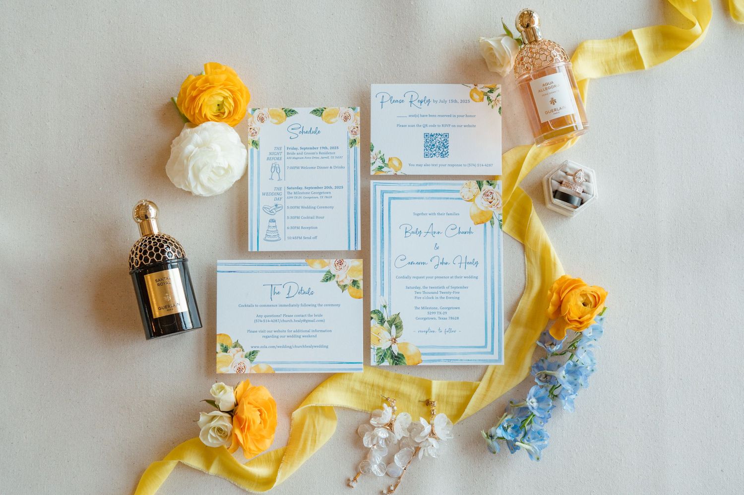 Wedding stationery flatlay with yellow flowers, blue ribbons, and elegant invitations on white linen background.