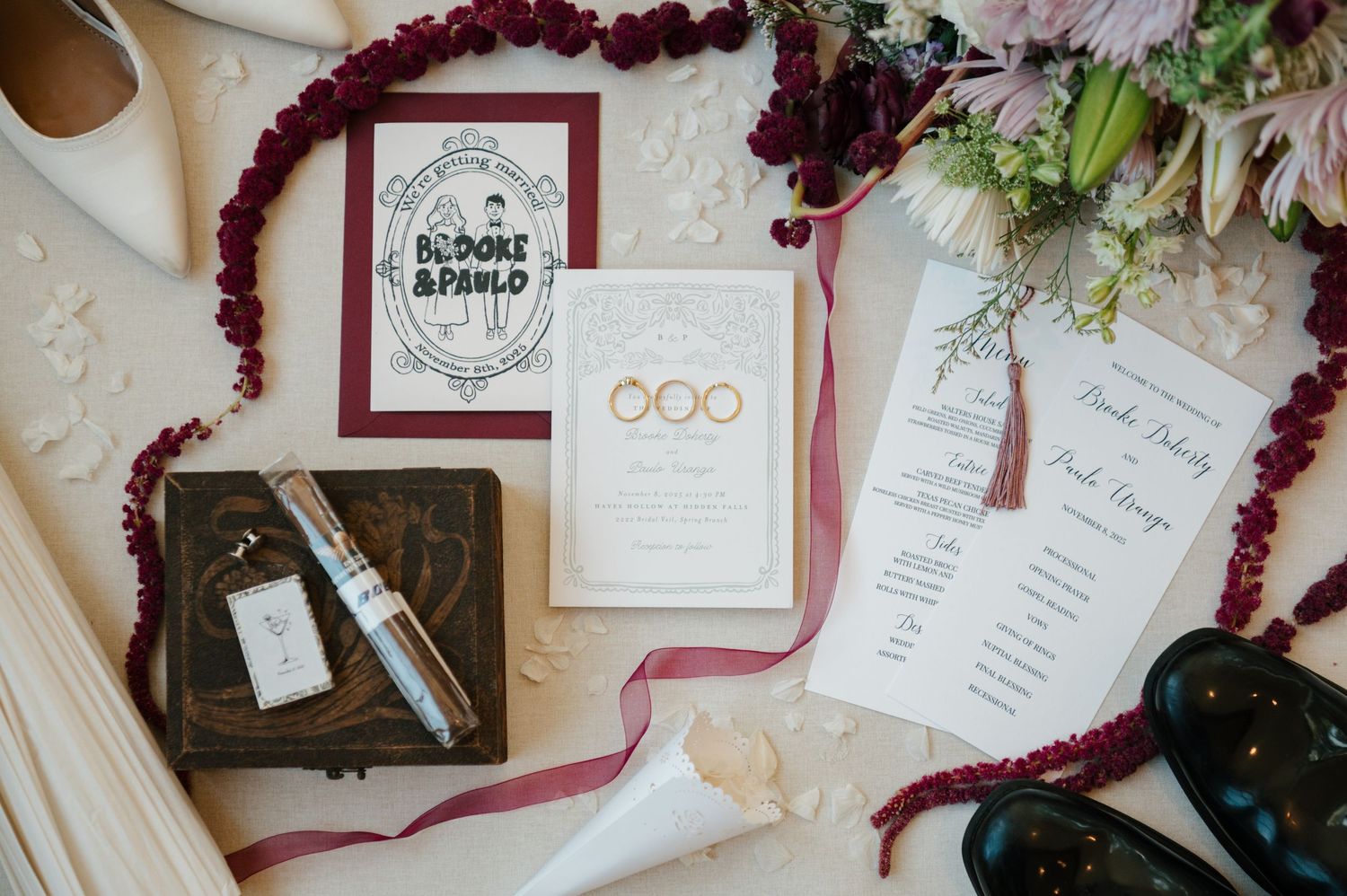 Wedding stationery and invitations laid out with burgundy florals and decorative elements on a light surface.