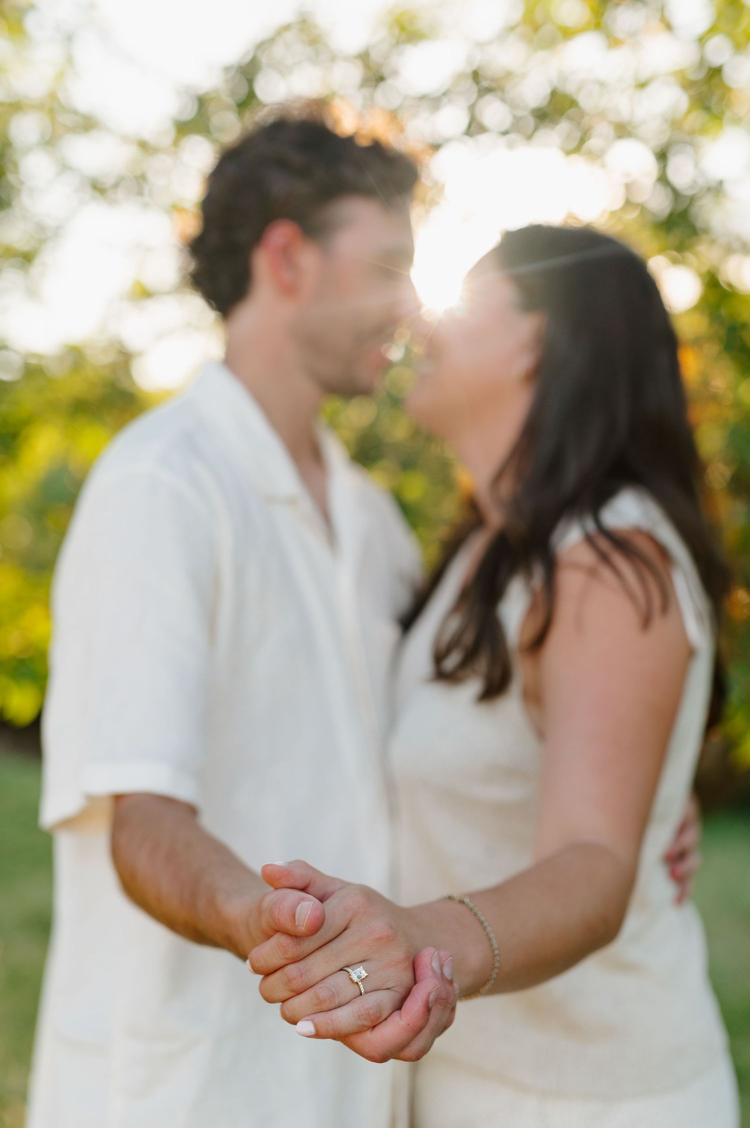 A couple shares an intimate dance outdoors against a natural backdrop of greenery and sunlight.
