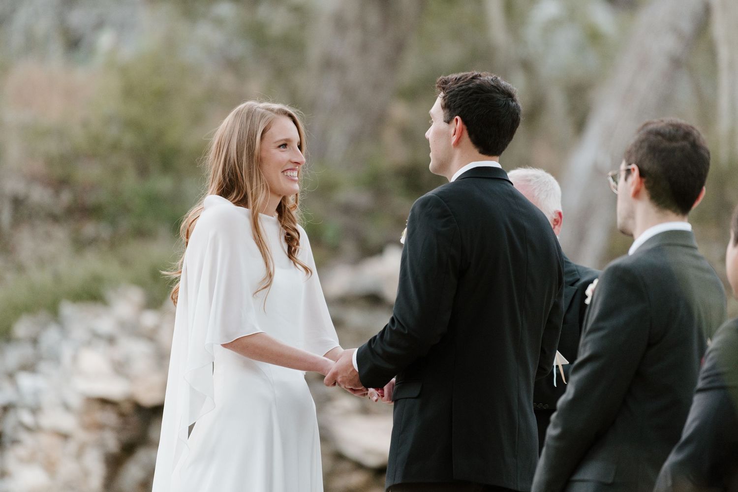 Outdoor wedding ceremony moment with guests watching under Spanish moss trees.