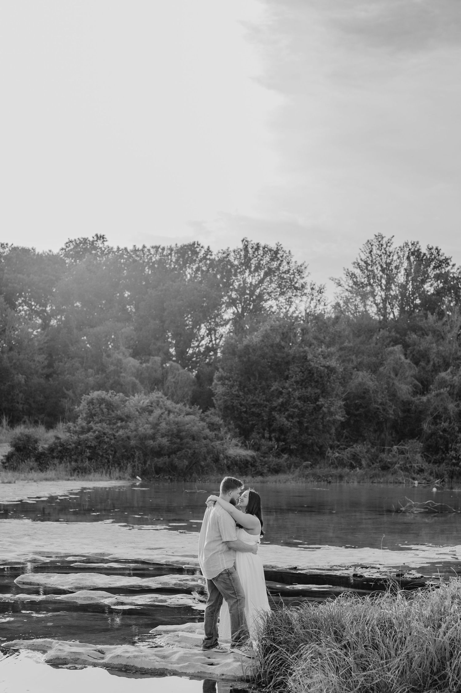 Black and white romantic panoramic sequence of a couple standing by a riverside on their wedding day.
