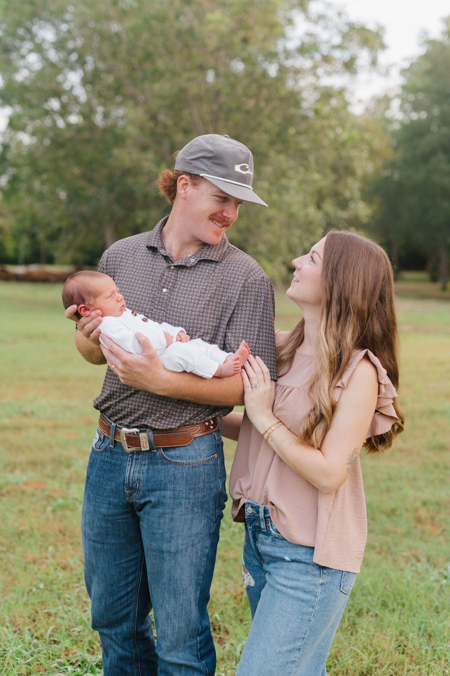 A sweet family moment captured in a series of candid outdoor photos on a grassy field during a photoshoot.