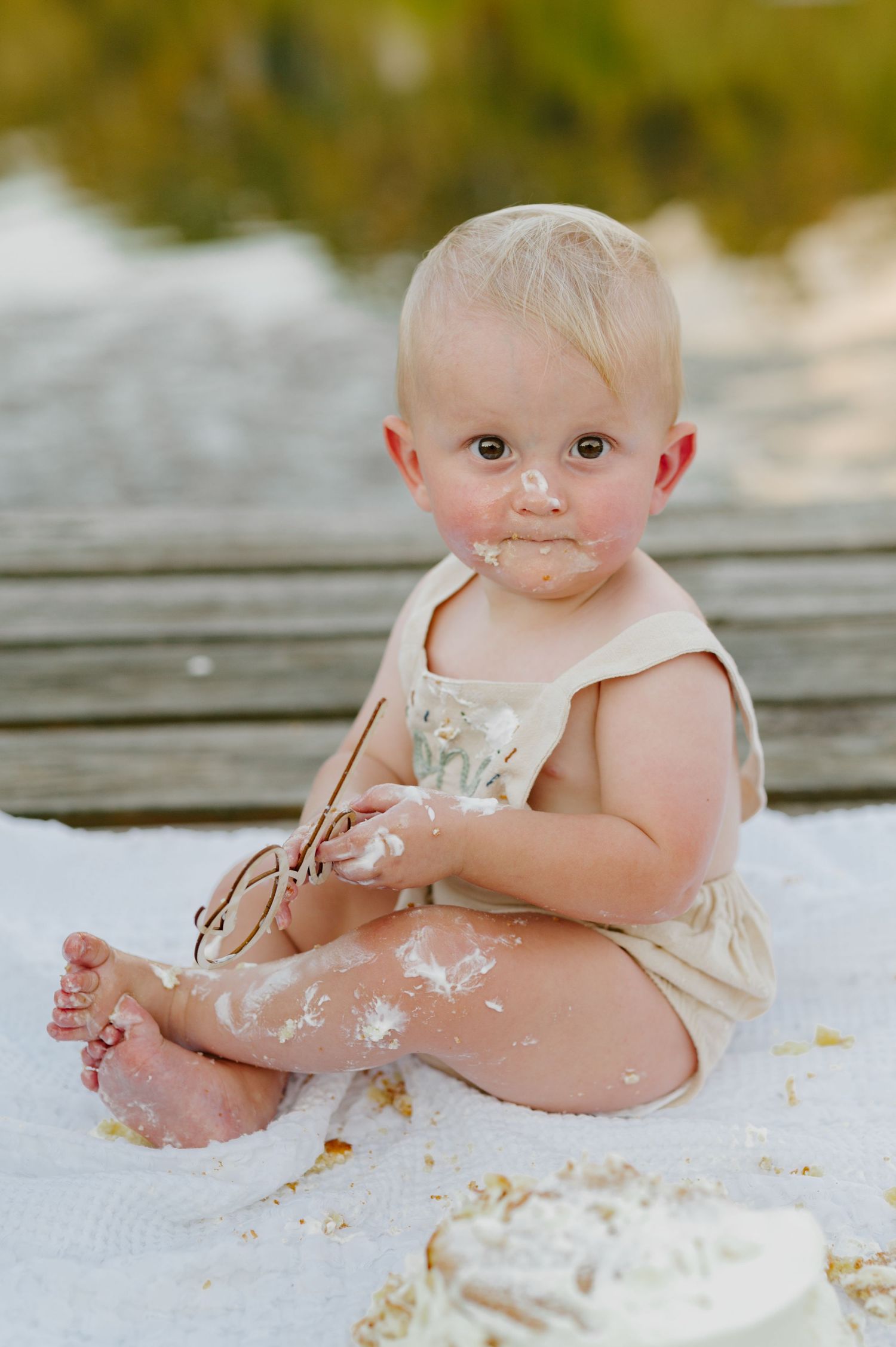 Baby sitting on white surface covered in flour while playing and making a mess during messy sensory play session.