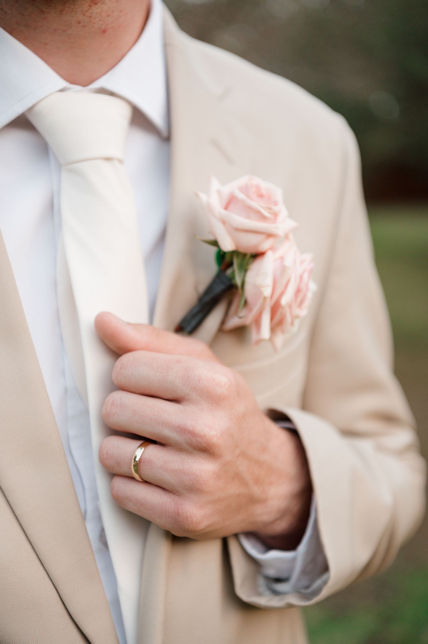 Detail shots of groom's tan suit with pink rose boutonniere and white tie.