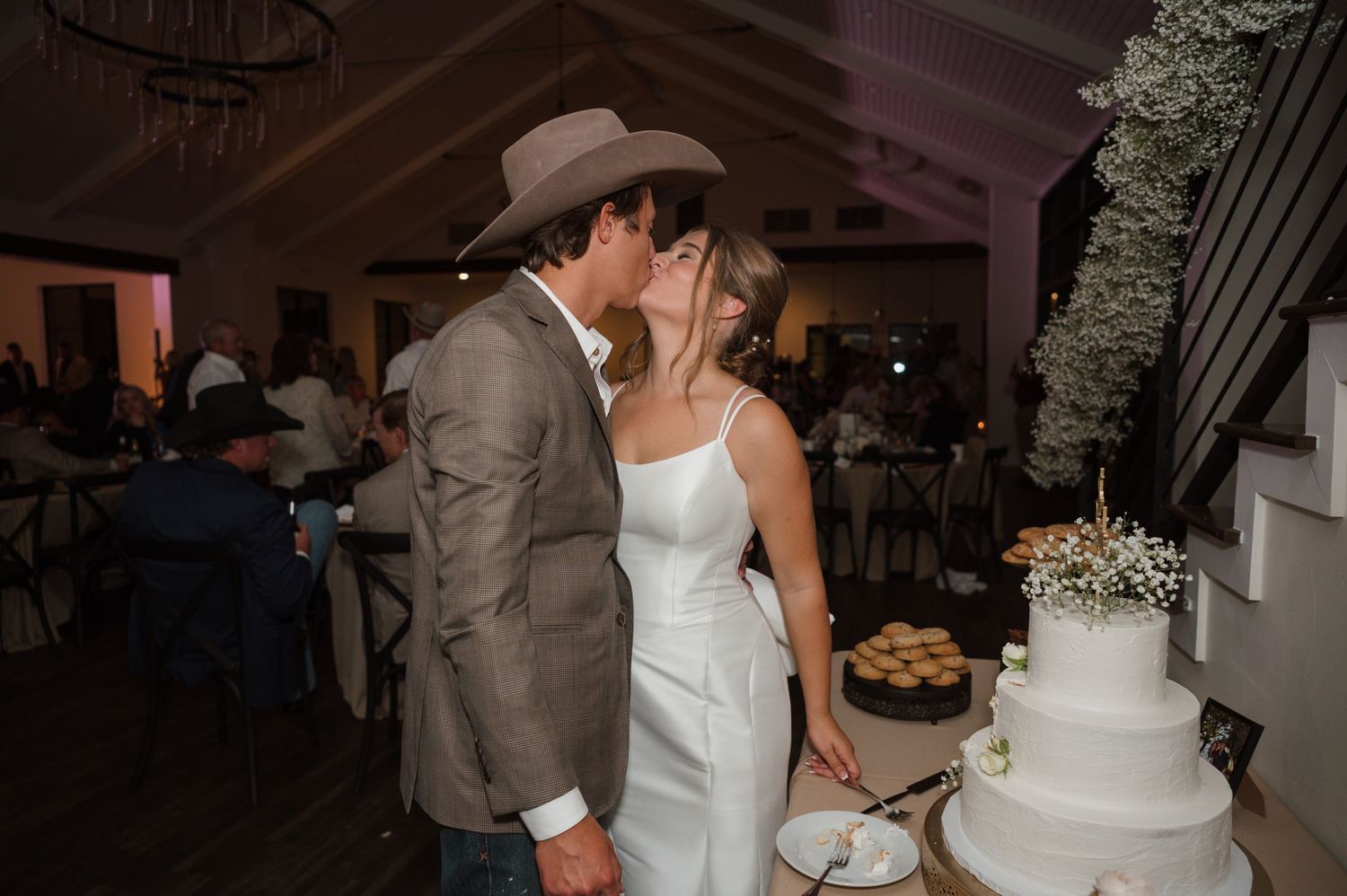 Wedding reception venue decorated with string lights showing couples dancing and celebrating.