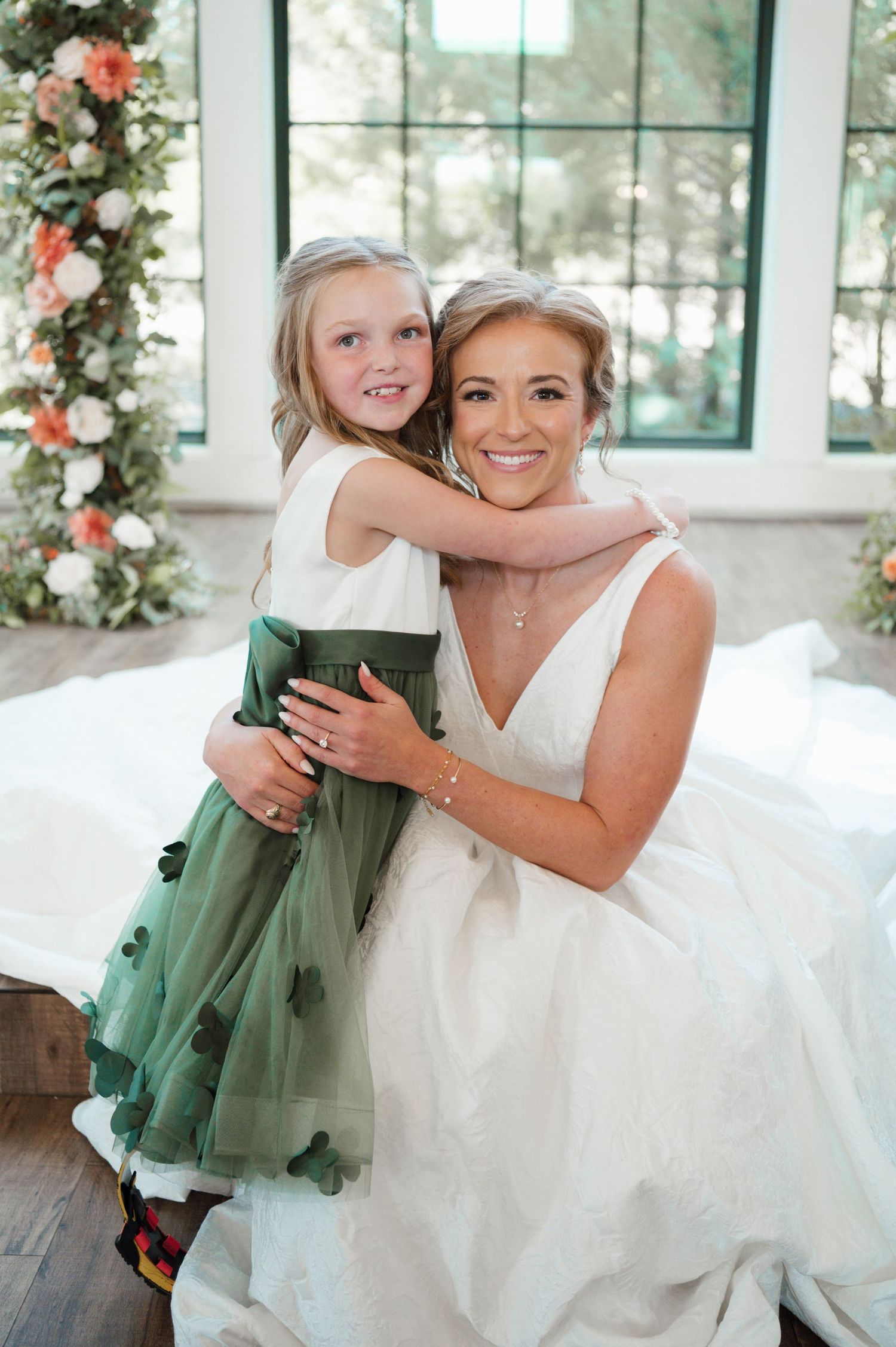 A heartwarming wedding moment captured indoors with floral decorations and elegant white dress.