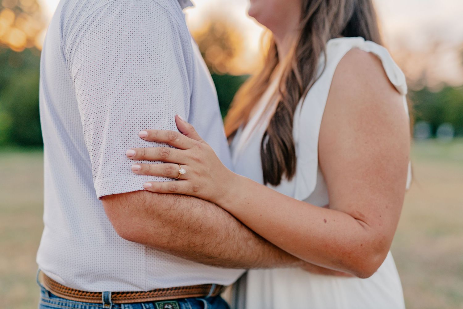 Close-up shot of hands embracing during an outdoor couples photoshoot.
