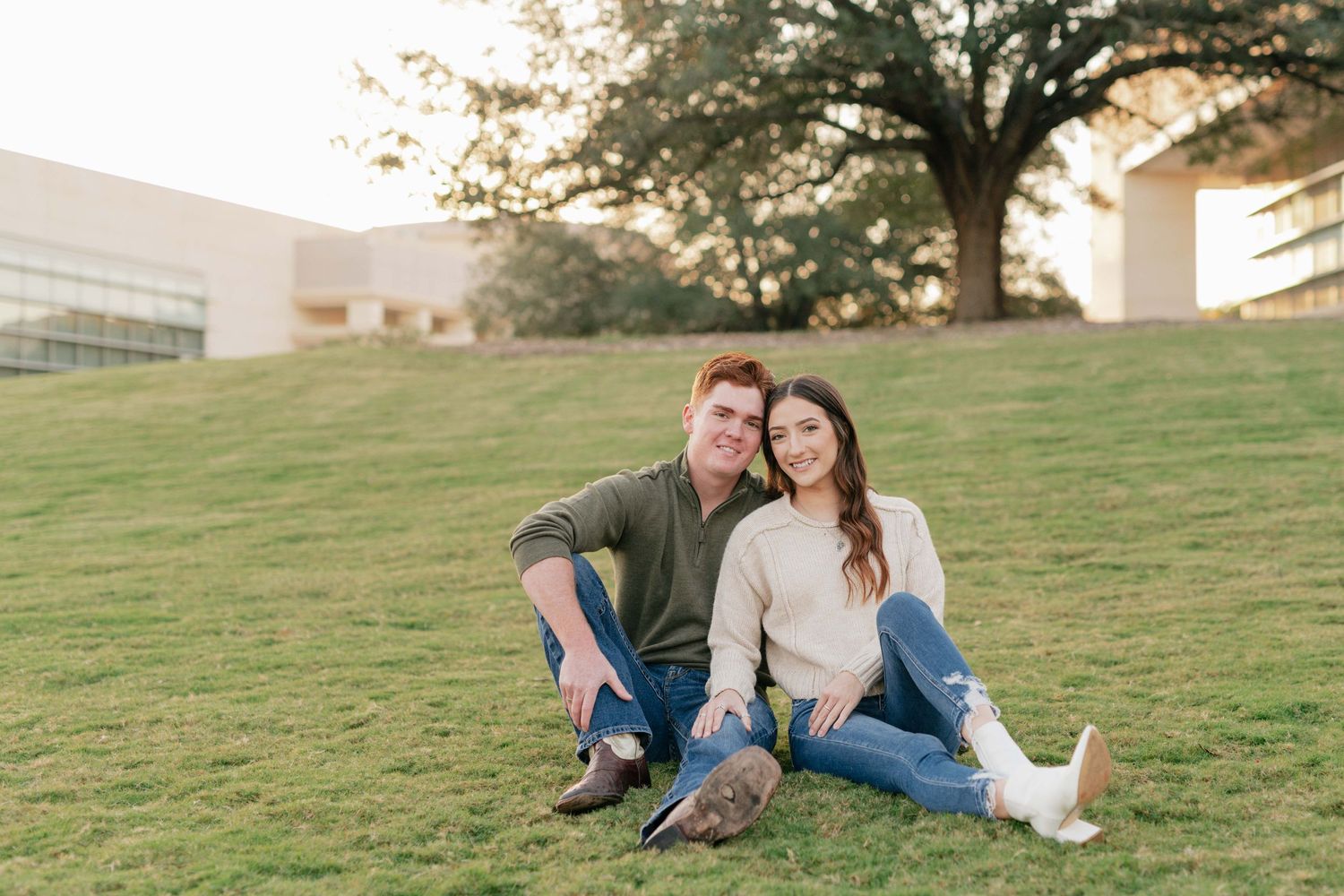 A couple relaxes together on a grassy hill during a warm autumn evening.
