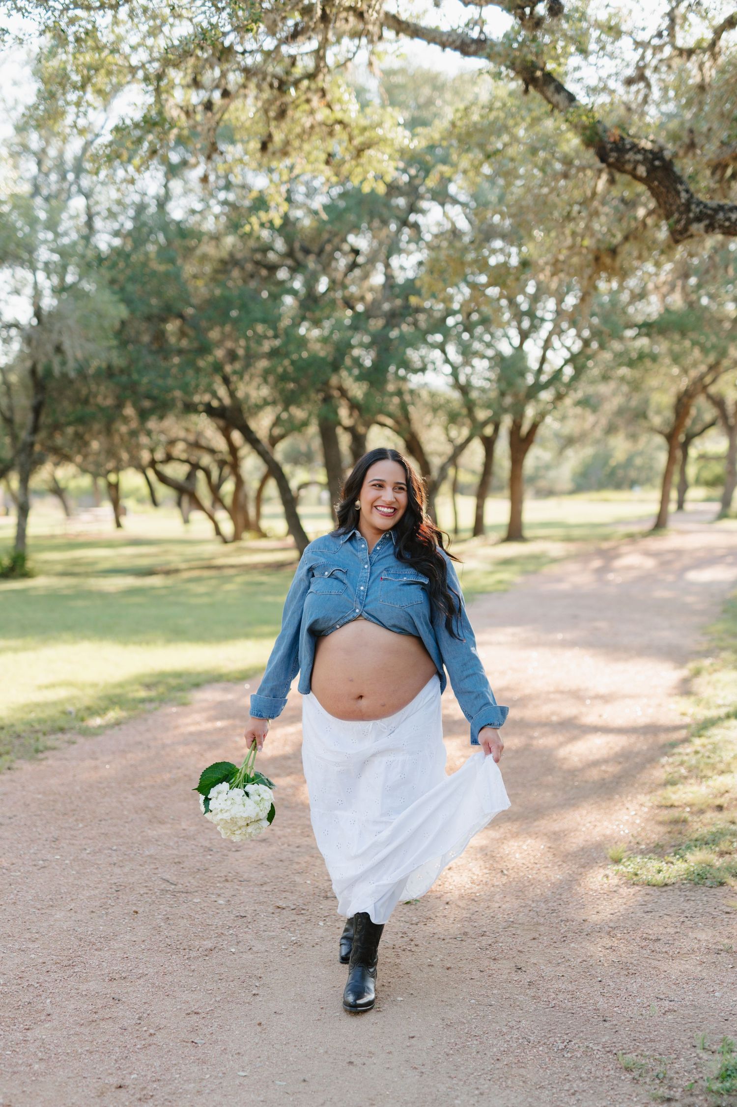 Maternity photo session captures joyful moments in a natural outdoor setting with oak trees.