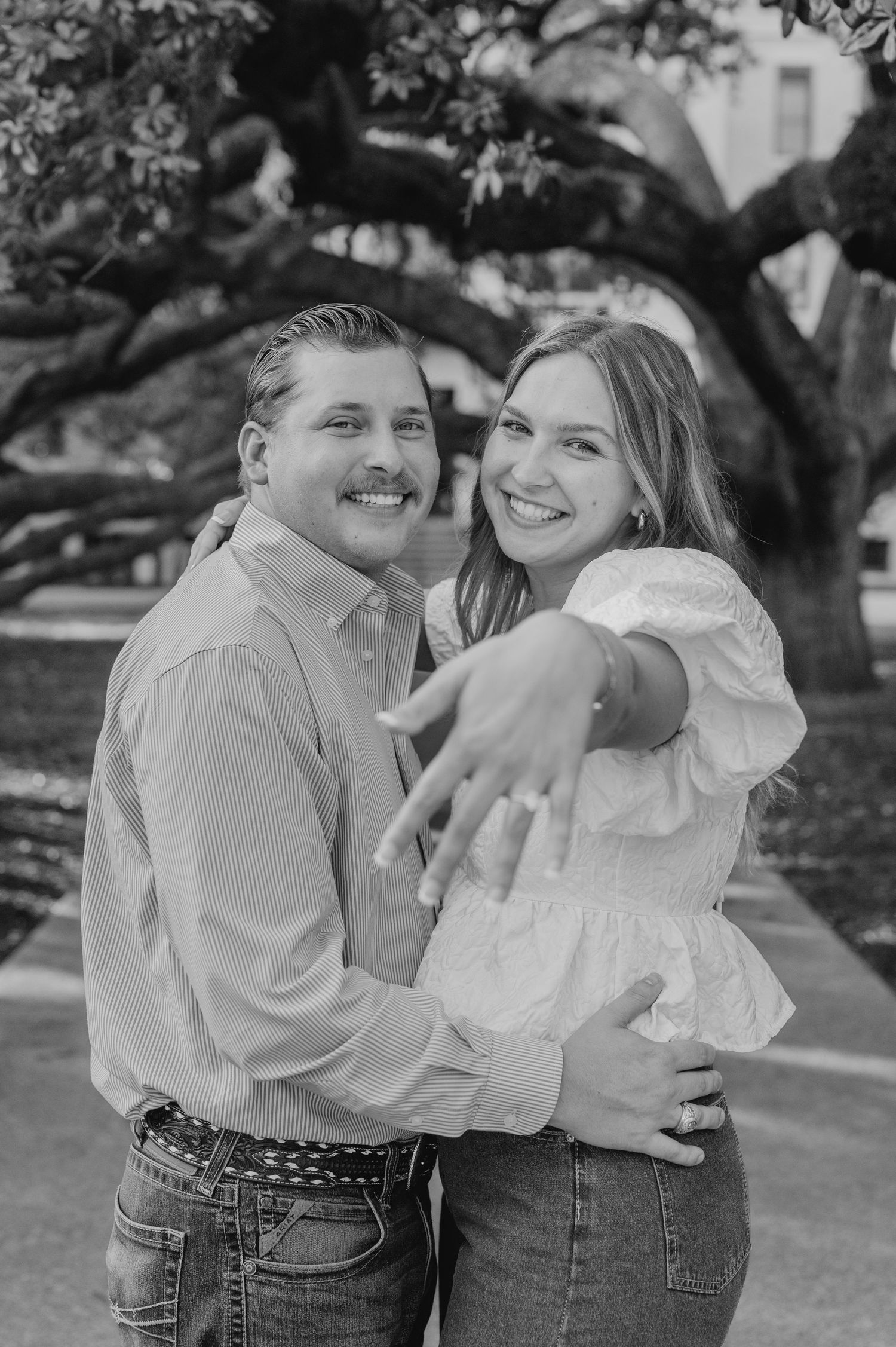 Black and white photo of a couple sharing sweet moments and laughter in casual outfits outdoors.
