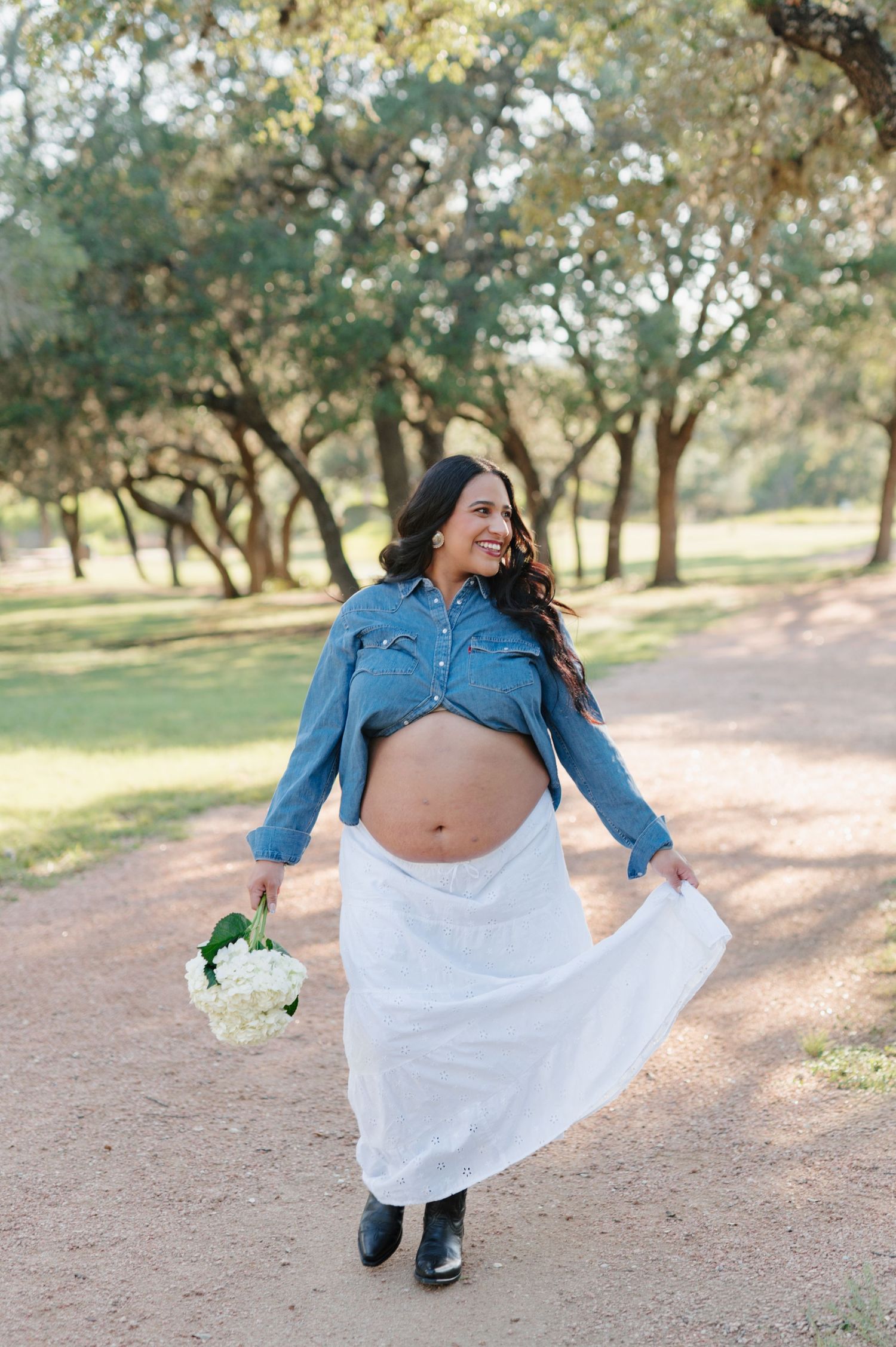 A joyful moment captured on a natural path with trees as someone dances and twirls in a white dress.
