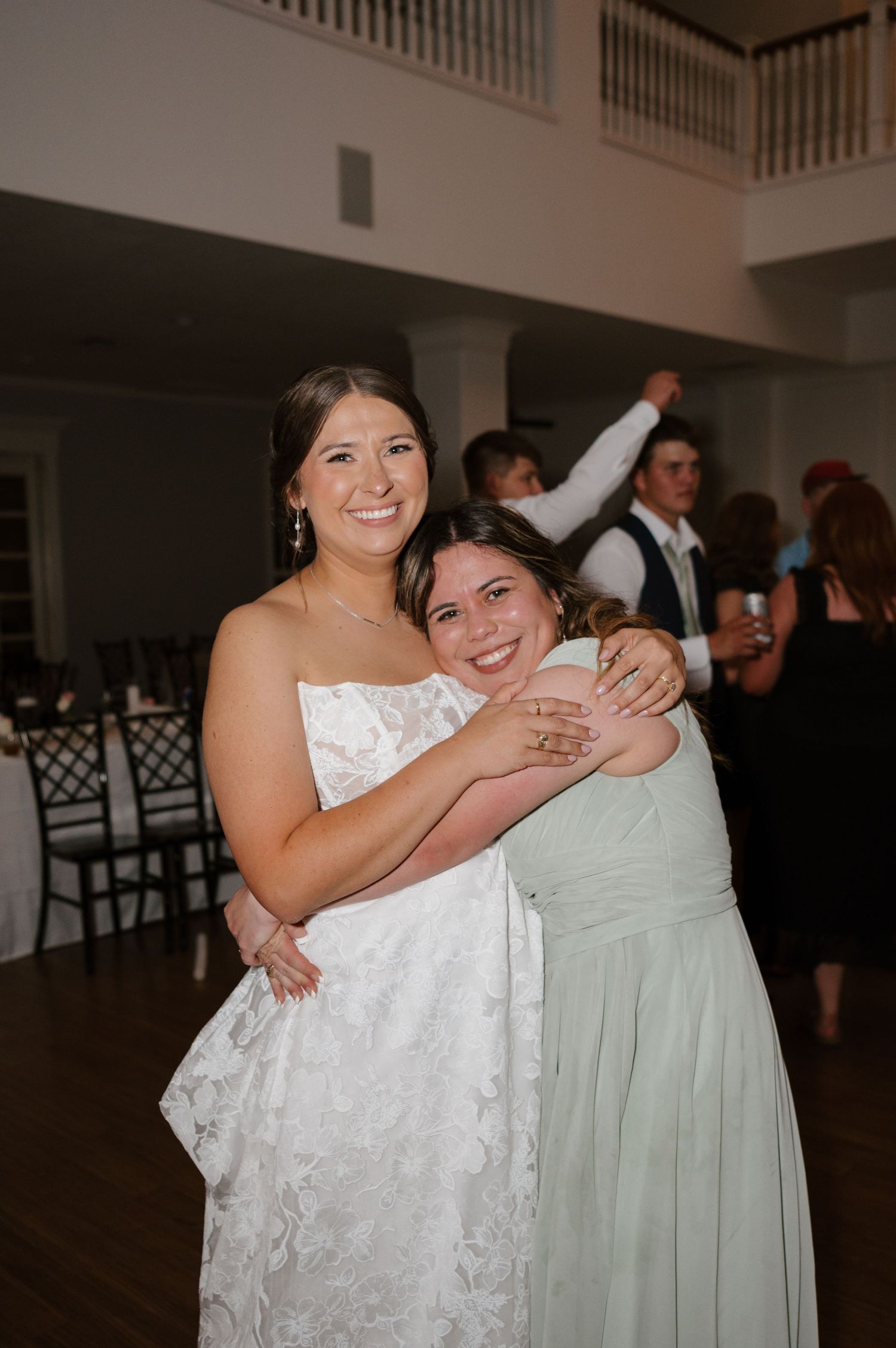 Two wedding guests sharing a joyful embrace on the dance floor.