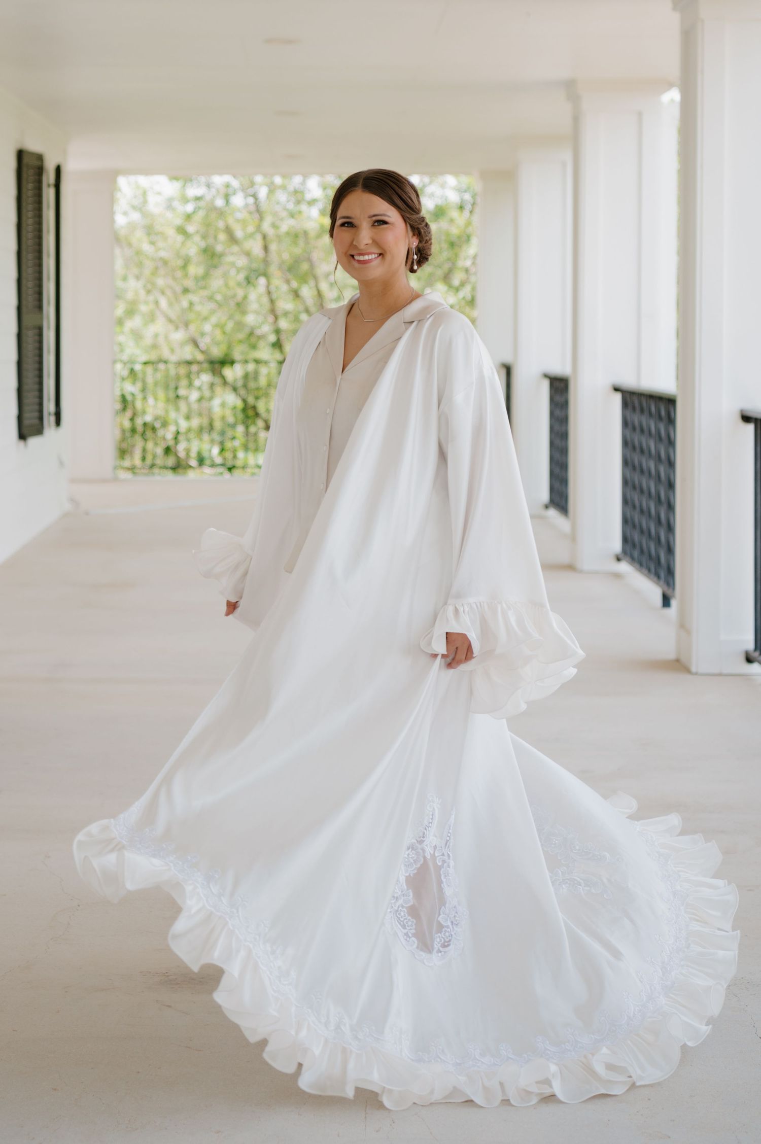 Beautiful white wedding dress twirling in an elegant covered outdoor porch setting.