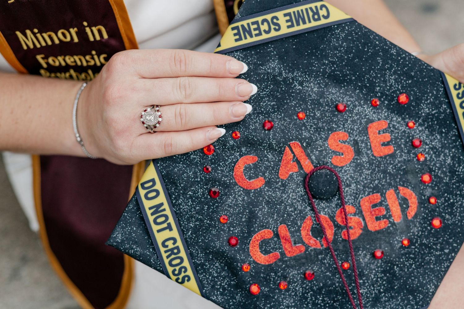 A decorated graduation cap with red text reading 'CASE CLOSED' against a black background.