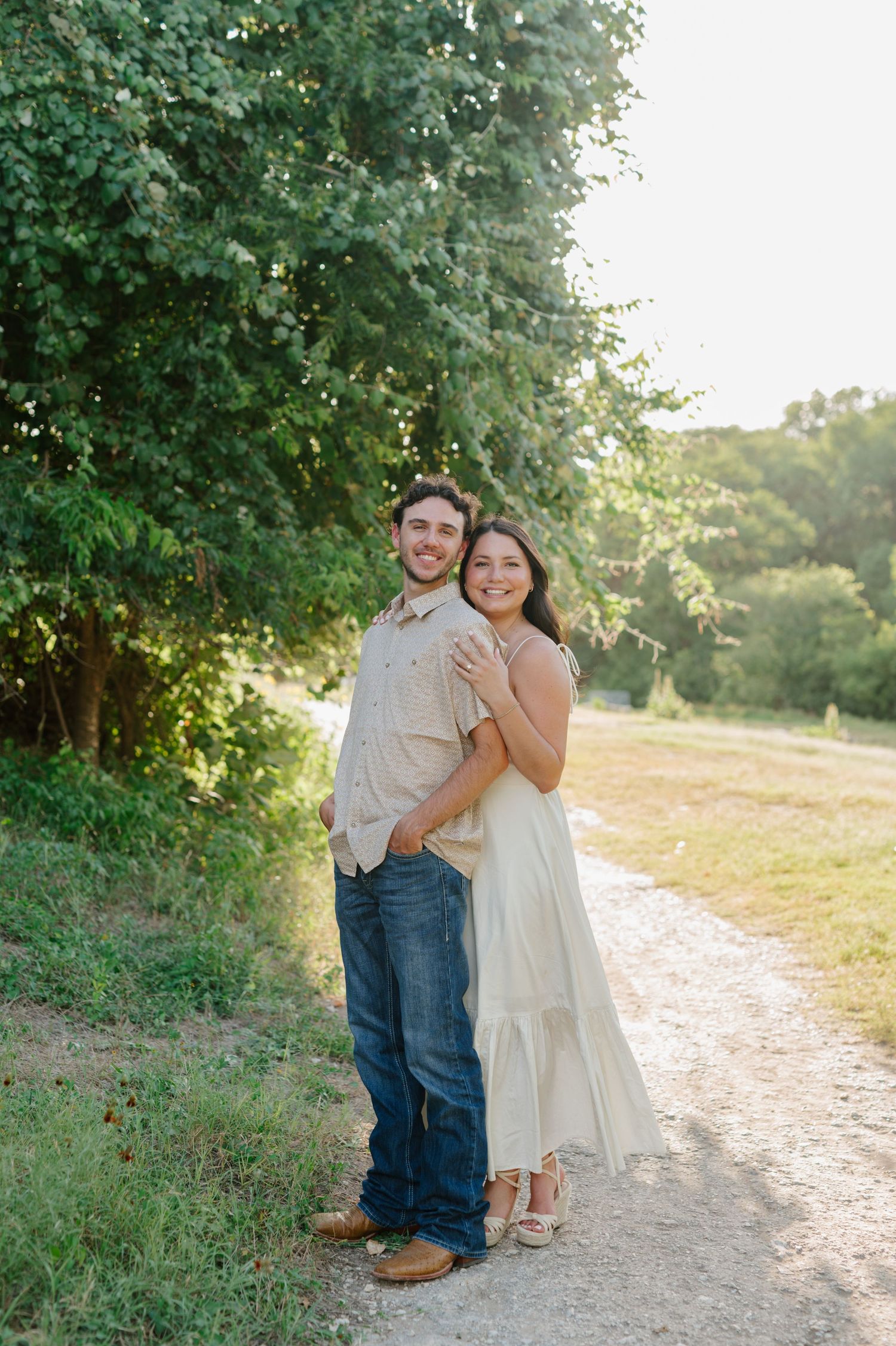 Sweet couple's portrait session on a dirt path surrounded by lush greenery.